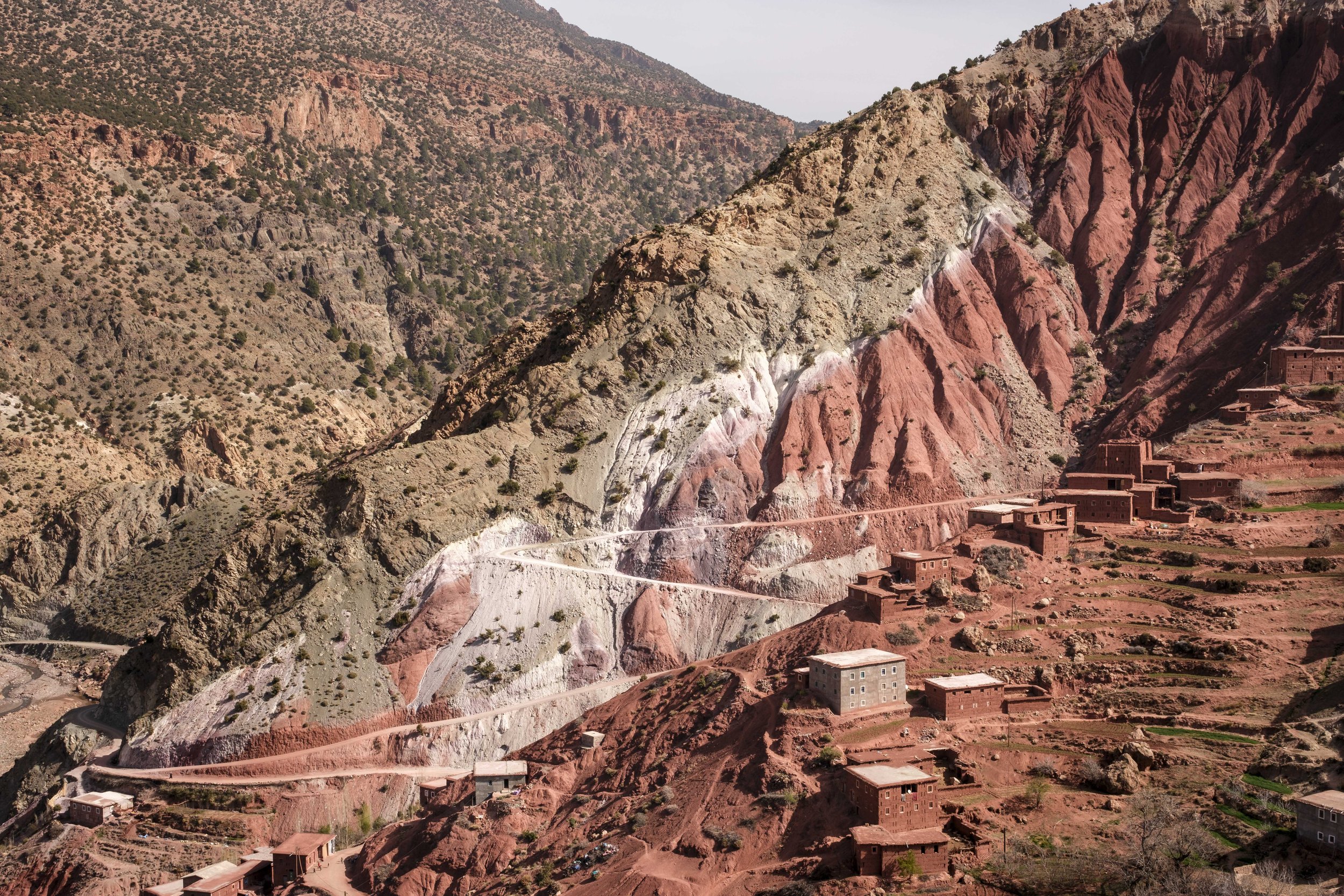 Red mountain cliffs and traditional villages along a winding road in Morocco’s High Atlas Mountains.
