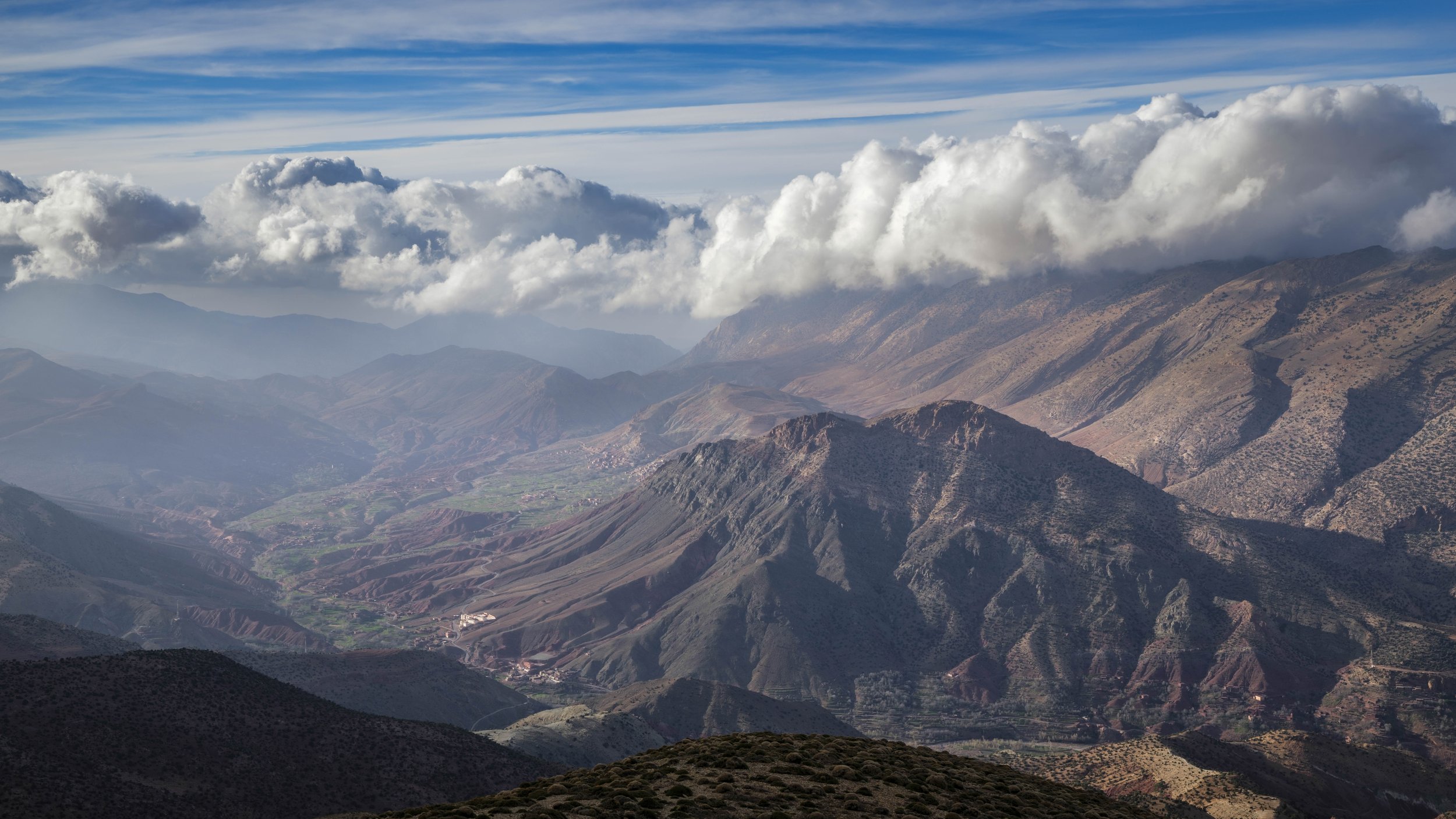 Clouds drifting above layered ridges of the High Atlas Mountains overlooking the Aït Bouguemez Valley.