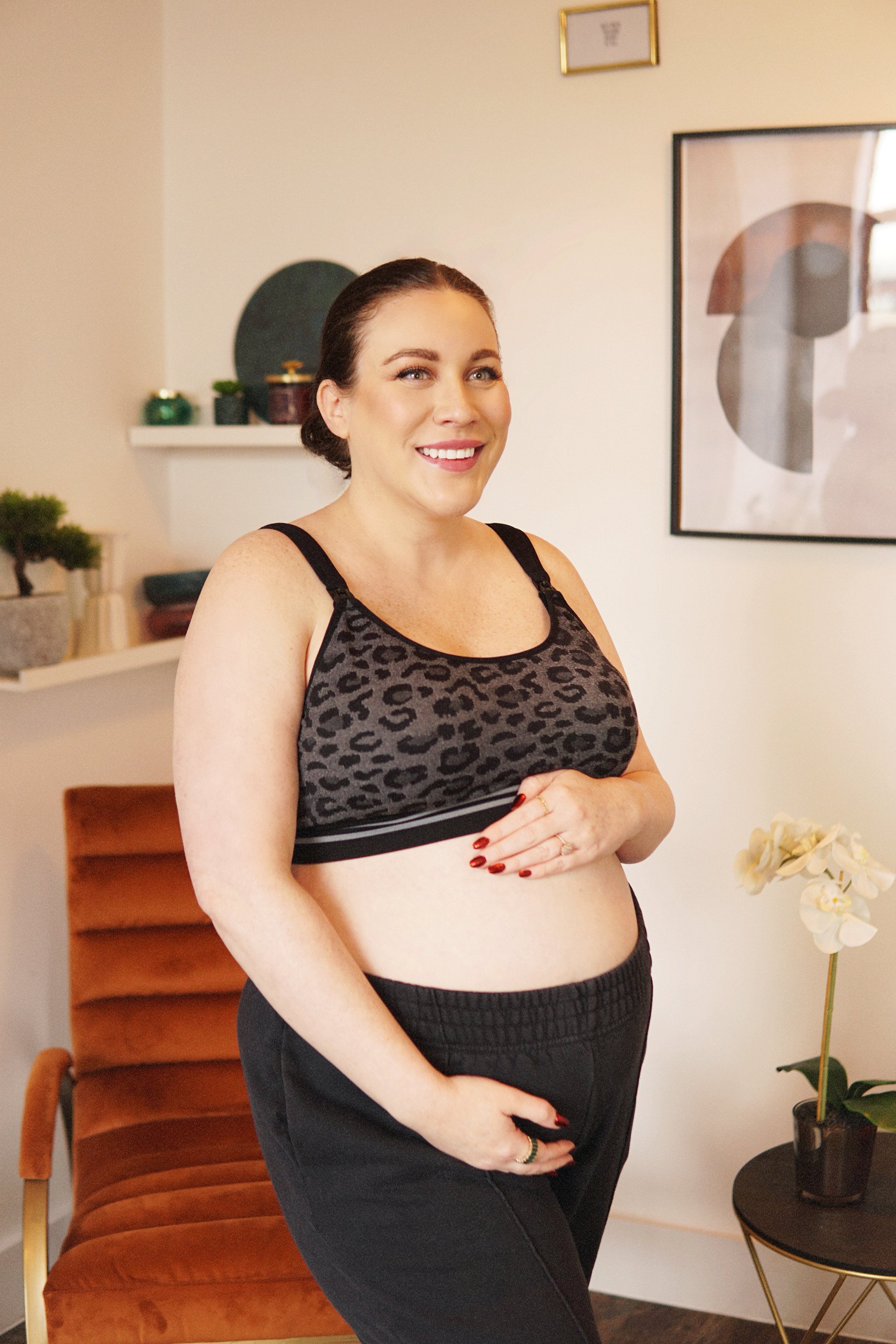 a pregnant Laura Barrett Larkins holds her belly wearing a momcozy sports bra