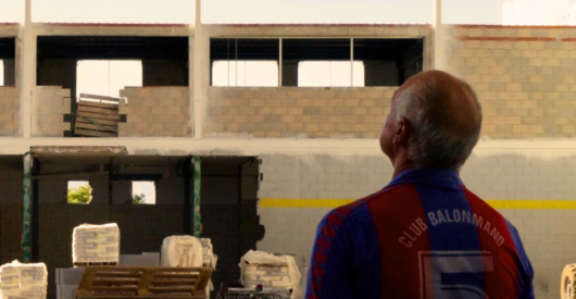 Un hombre con camiseta de balonmano observa una construcción en proceso.