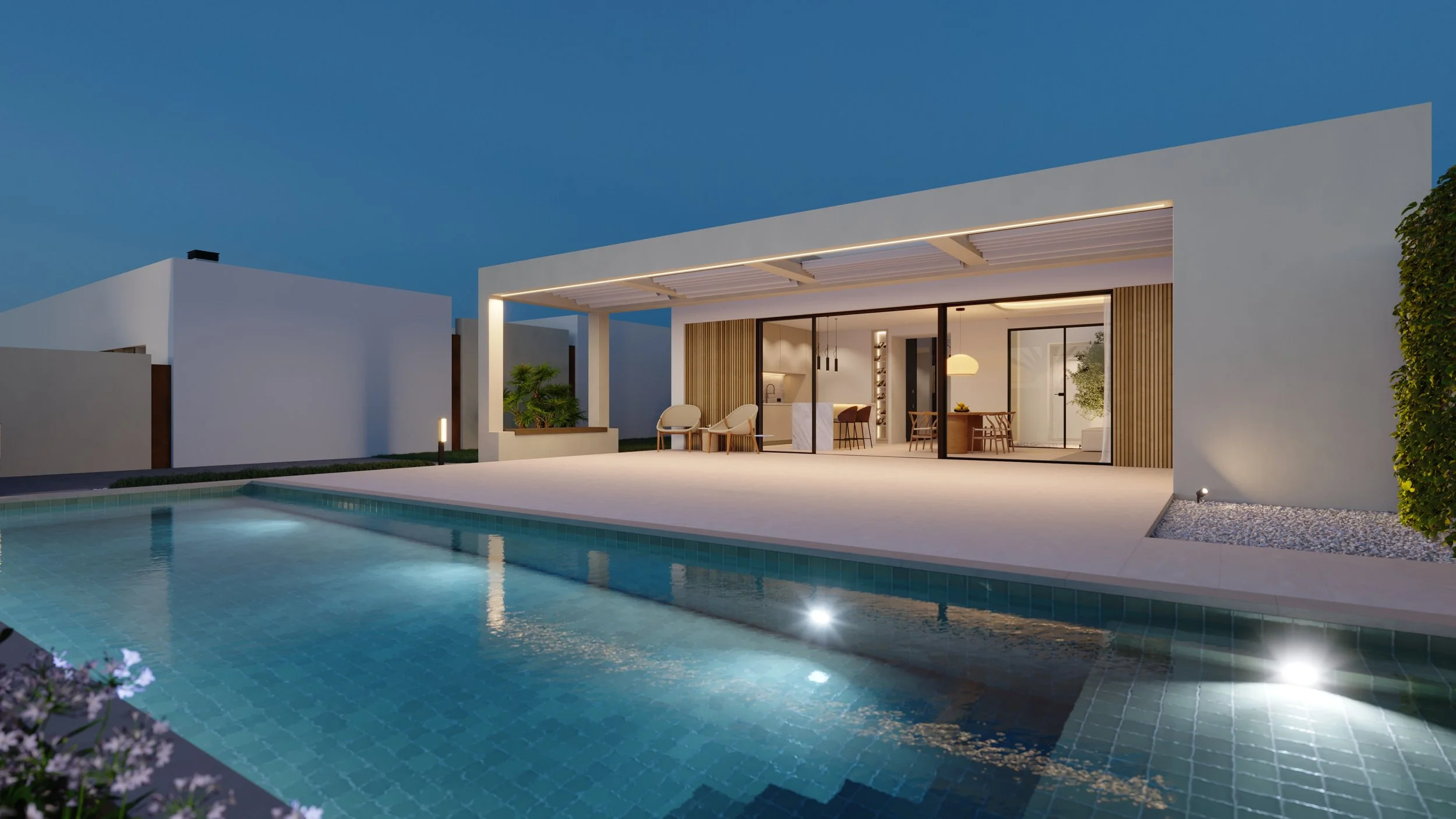 Casa moderna con piscina iluminada en la noche, área de descanso con sillas y comedor interior visible a través de puertas de vidrio.