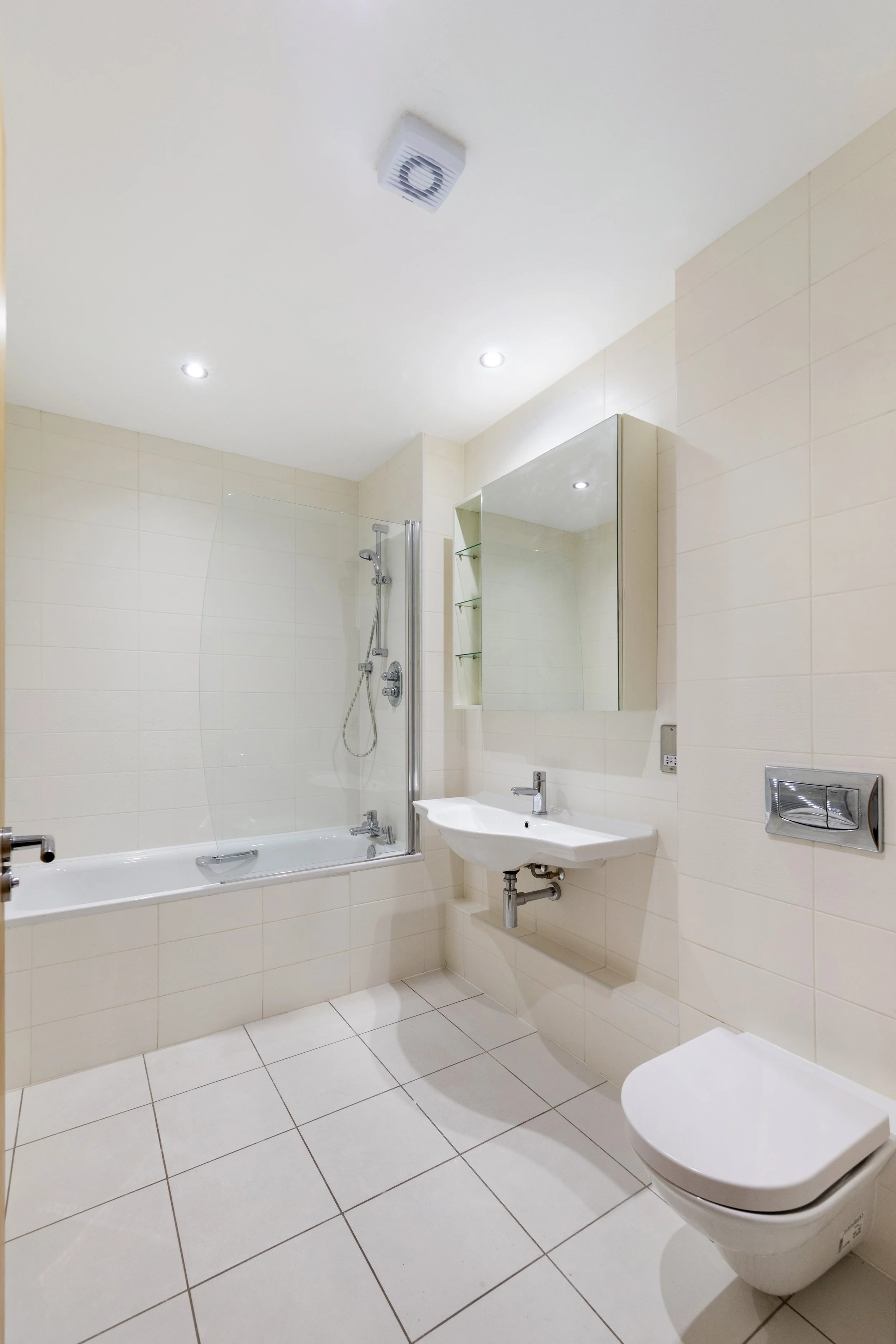 A clean, modern bathroom with a bathtub, shower, wall-mounted sink, mirror, and a wall-mounted toilet.