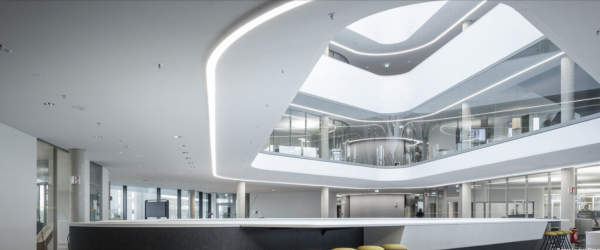 Interior of a modern, multi-story shopping mall with curved architecture and glass railings.