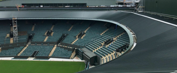Empty stadium with rows of seats and a grass field, viewed from above.
