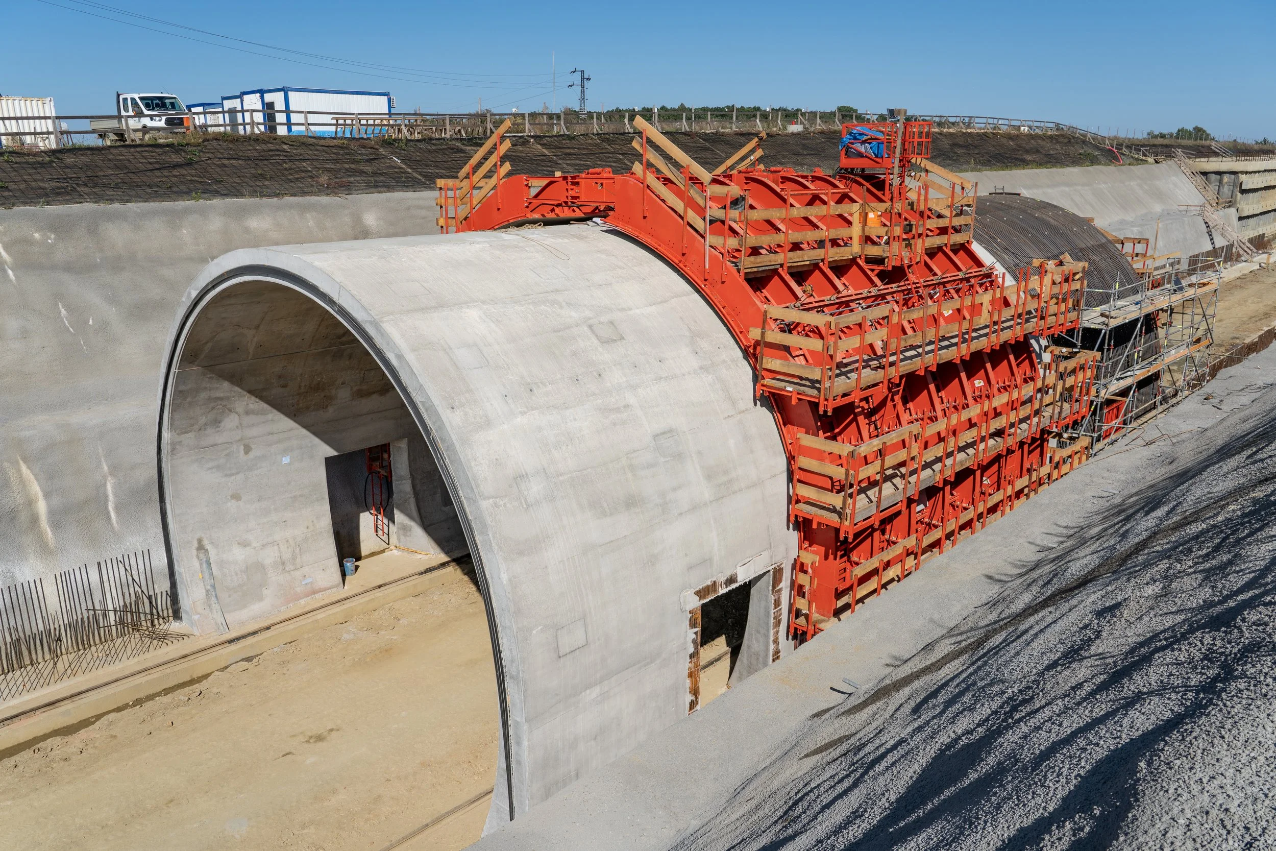 Under construction tunnel with concrete arch and orange scaffolding.