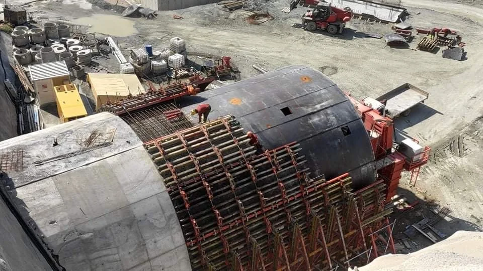 Construction workers assembling a tunnel segment with rebar and scaffolding at a construction site.