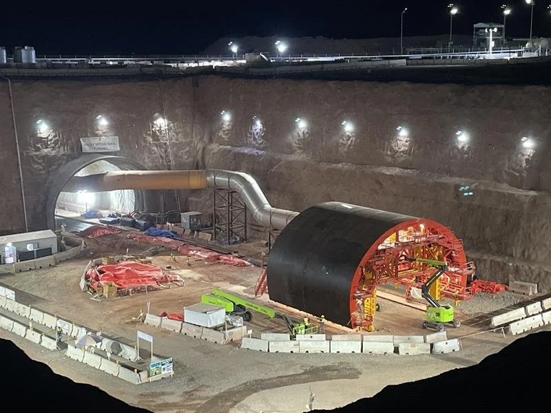 Construction site inside a tunnel with heavy machinery and equipment at night.
