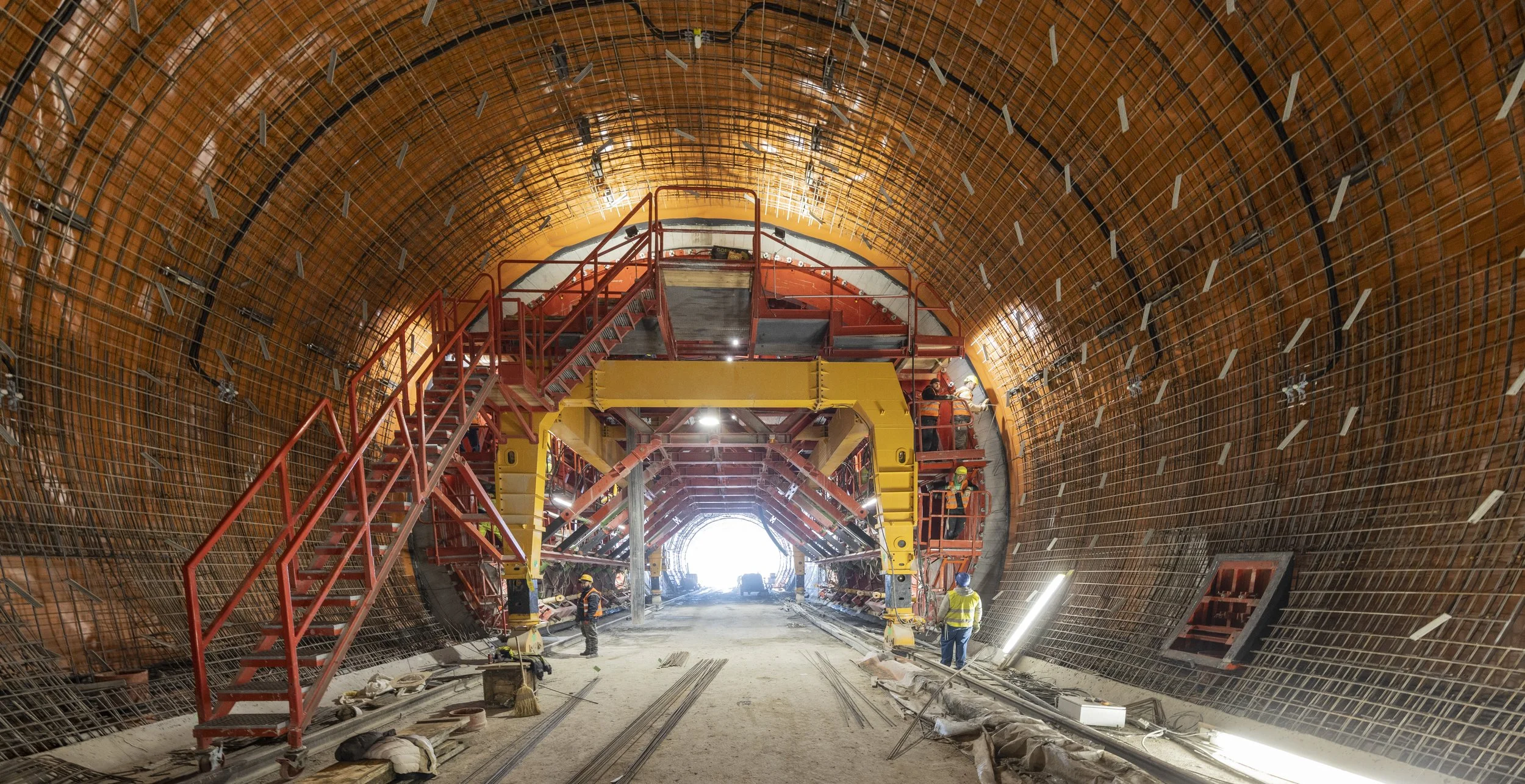 Underground tunnel construction with workers, scaffolding, and wood framing