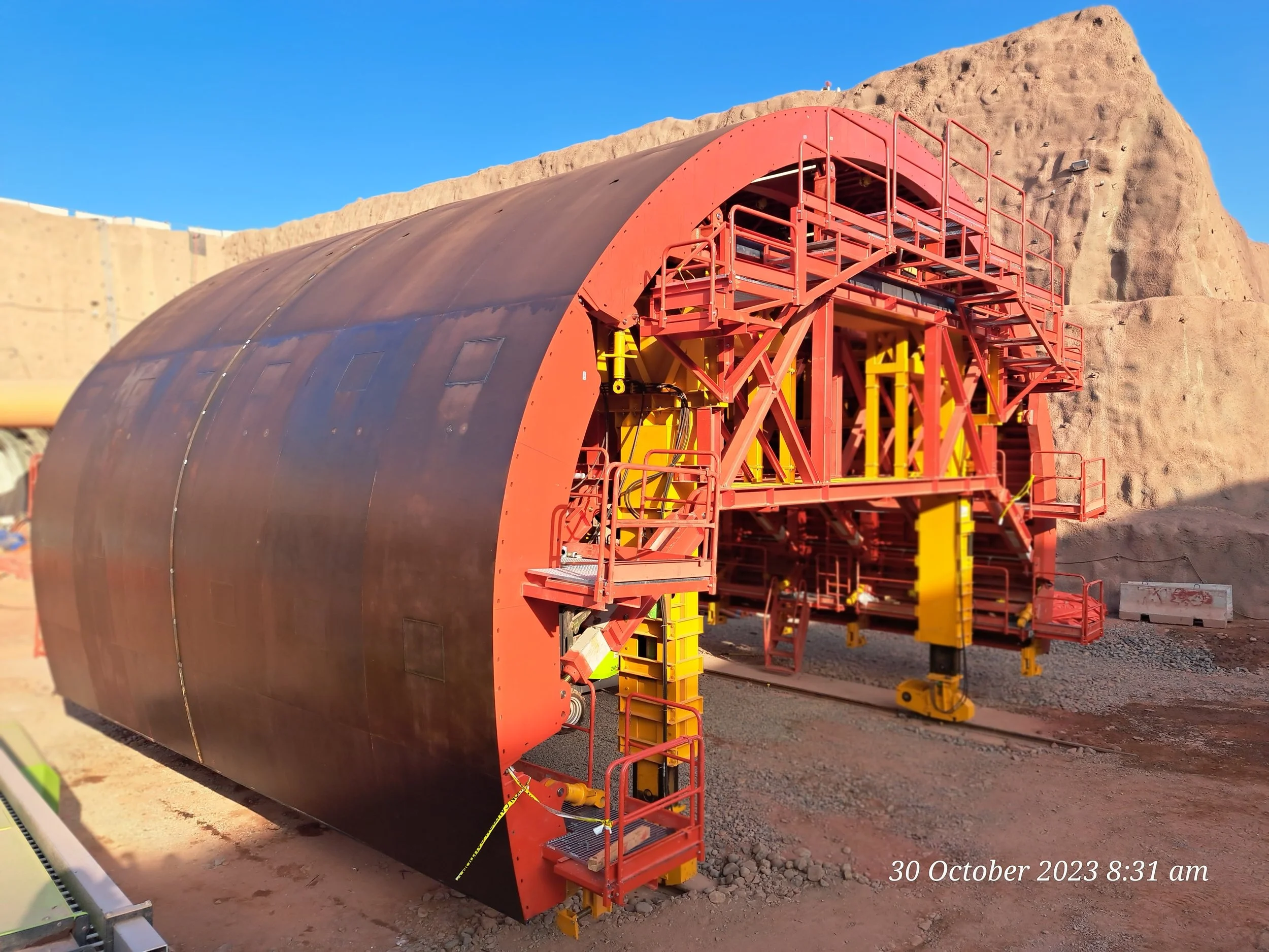 Large industrial tunnel boring machine at a construction site with rocky hills in the background, date and time overlayed as 30 October 2023 8:31 am.