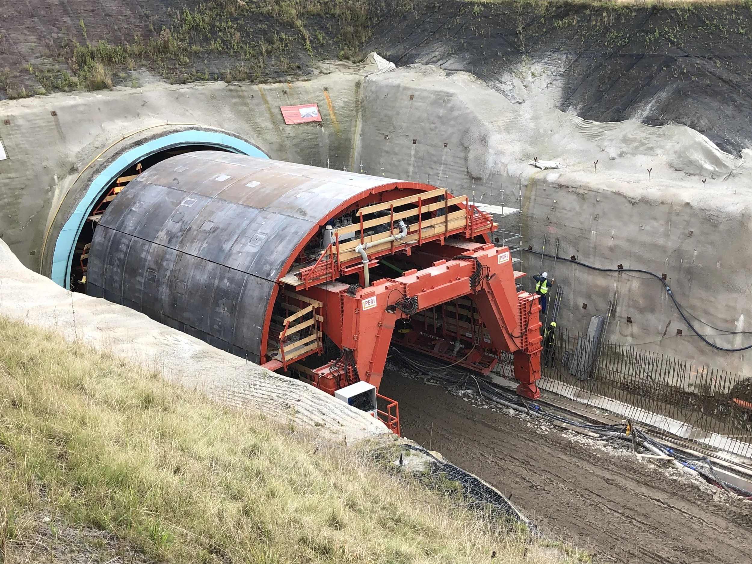 Large tunnel boring machine underground, surrounded by construction workers in a dirt and rock excavation site.