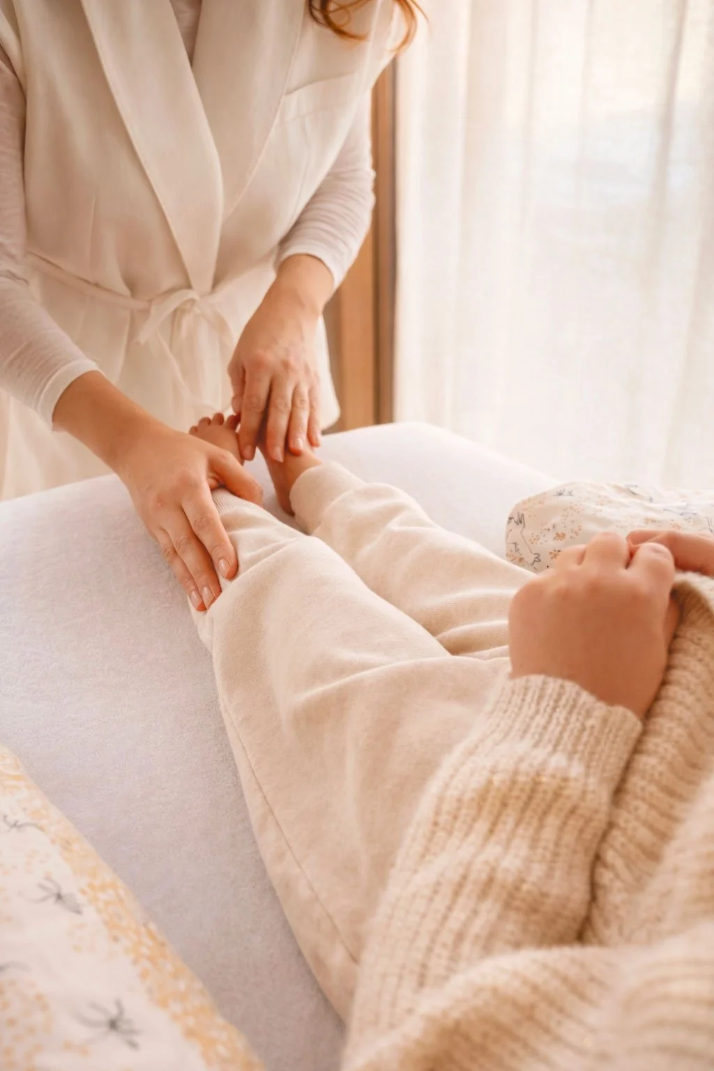Une personne donne un massage à une autre personne allongée sur une table, dans une pièce lumineuse et chaleureuse.
