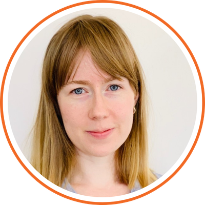 Close-up of a woman with long red hair and blue eyes, smiling softly against a plain white background.
