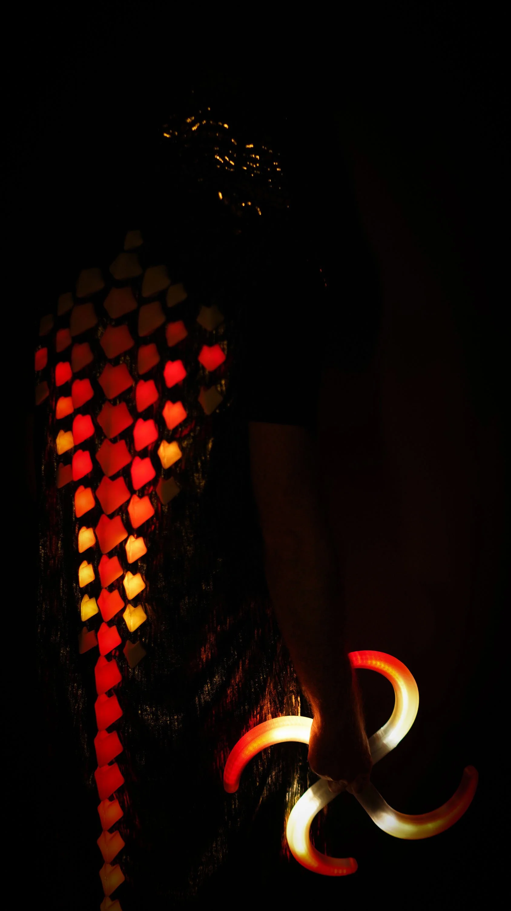 Performer using Alpha Kilo Victor Finger Buugeng programmable LED flow toys with a red and orange lighting pattern