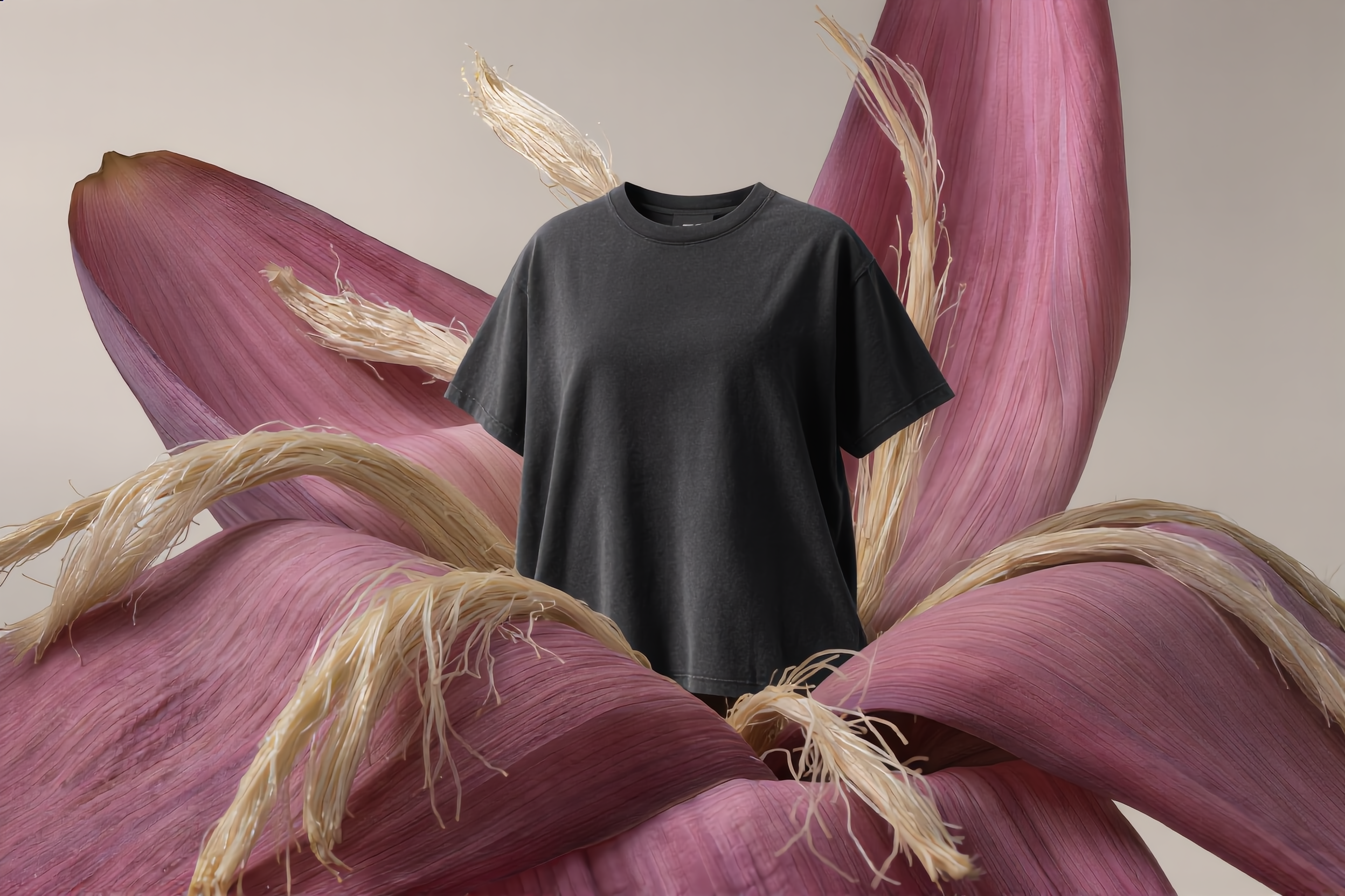 A black T-shirt displayed in front of a large pinkish-red flower with yellowish stalks.
