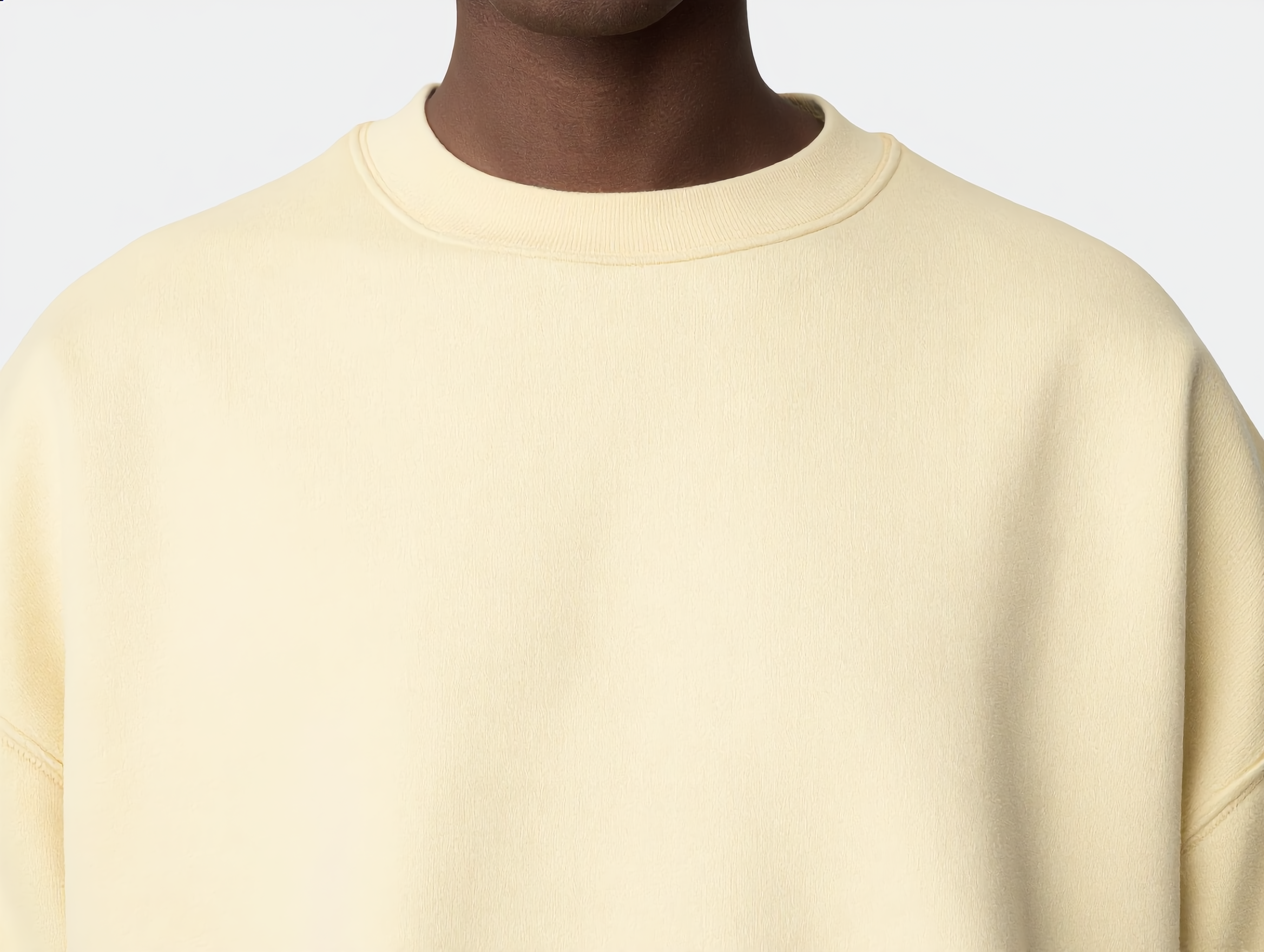 Close-up of a person wearing a cream-colored sweatshirt, focusing on the upper chest and neck area.