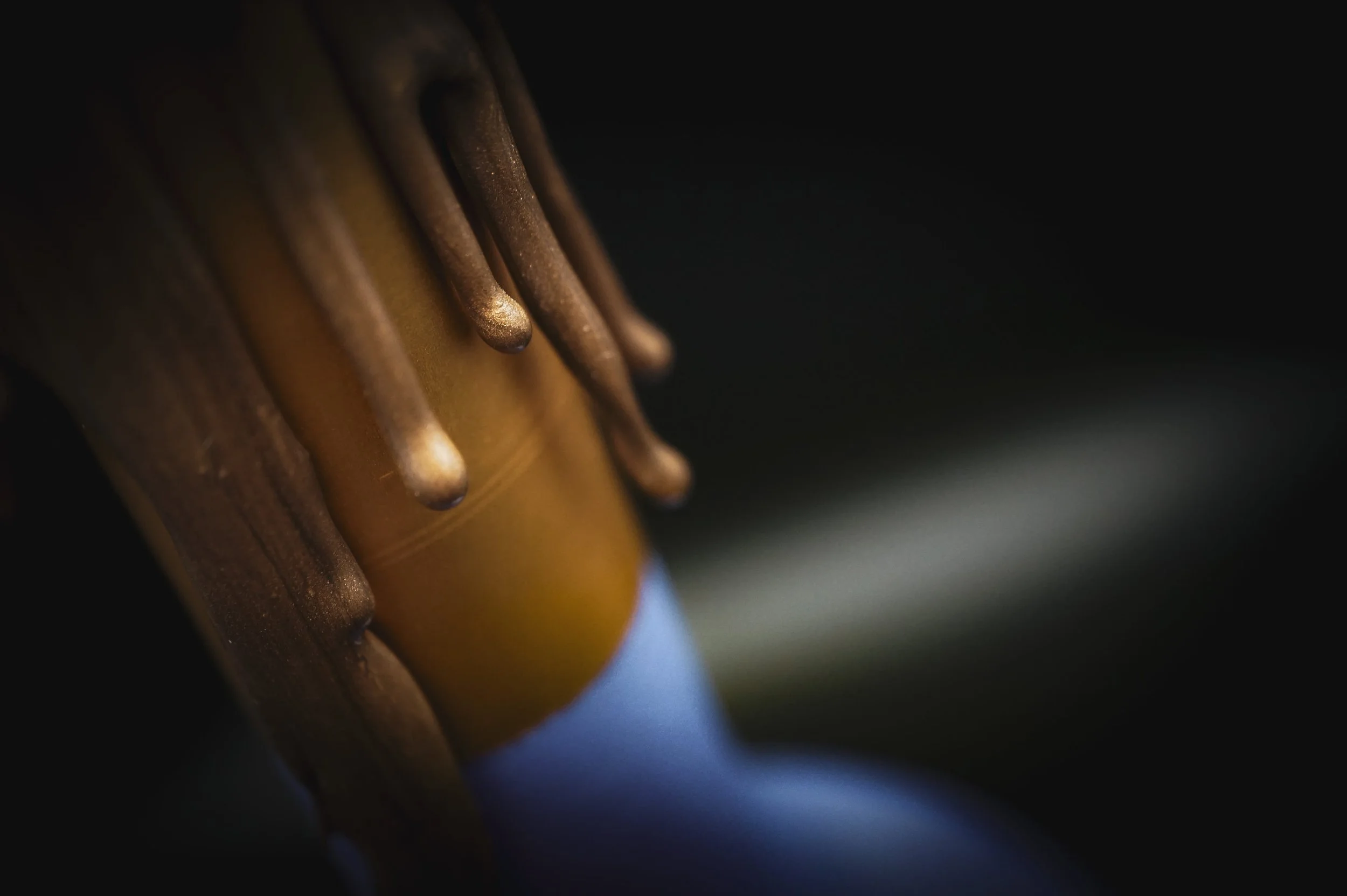 Macro close-up of gold wax texture detail on a hand-painted champagne bottle