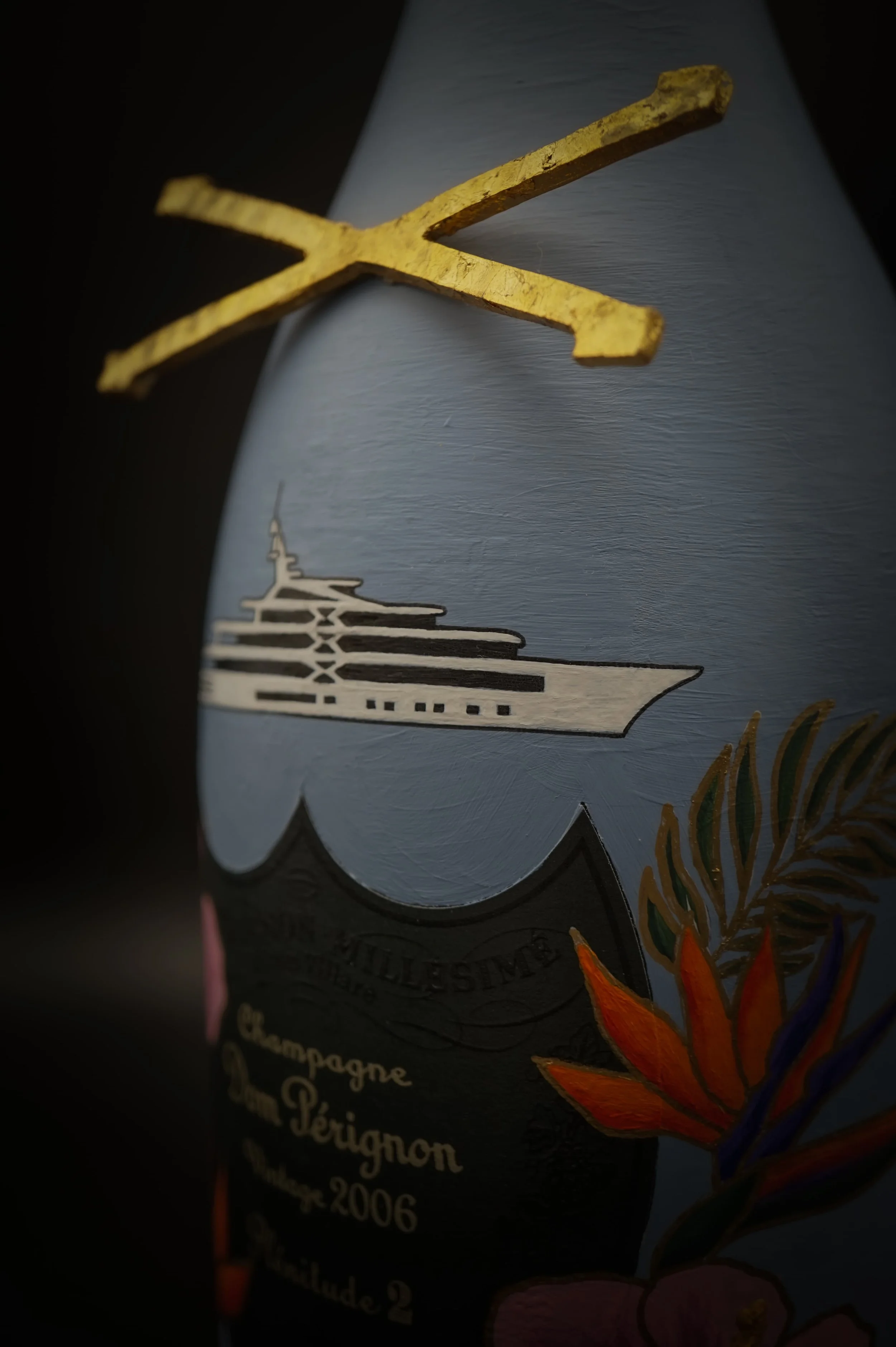 Hand-painted Dom Pérignon Vintage 2006 champagne bottle with superyacht illustration, gold cross detail, and tropical botanical motifs
