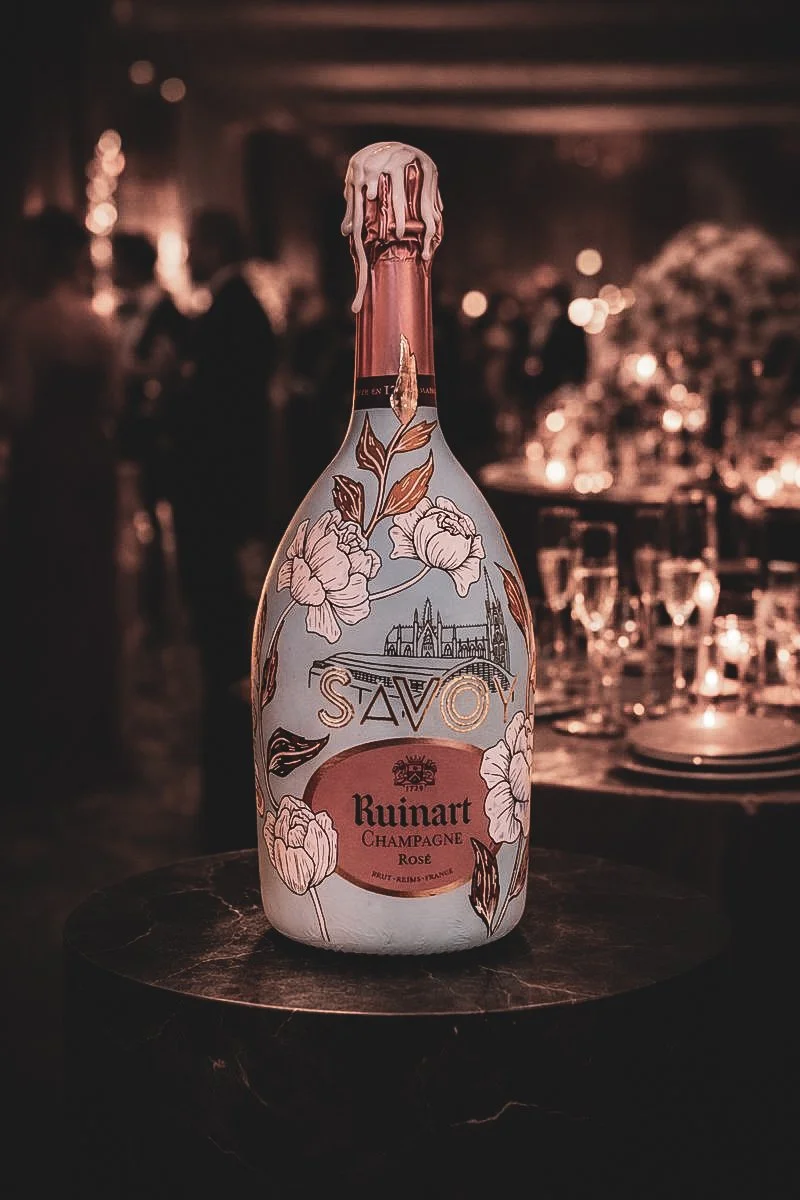 Hand-painted Ruinart Rosé champagne bottle with floral illustration displayed at an elegant evening event