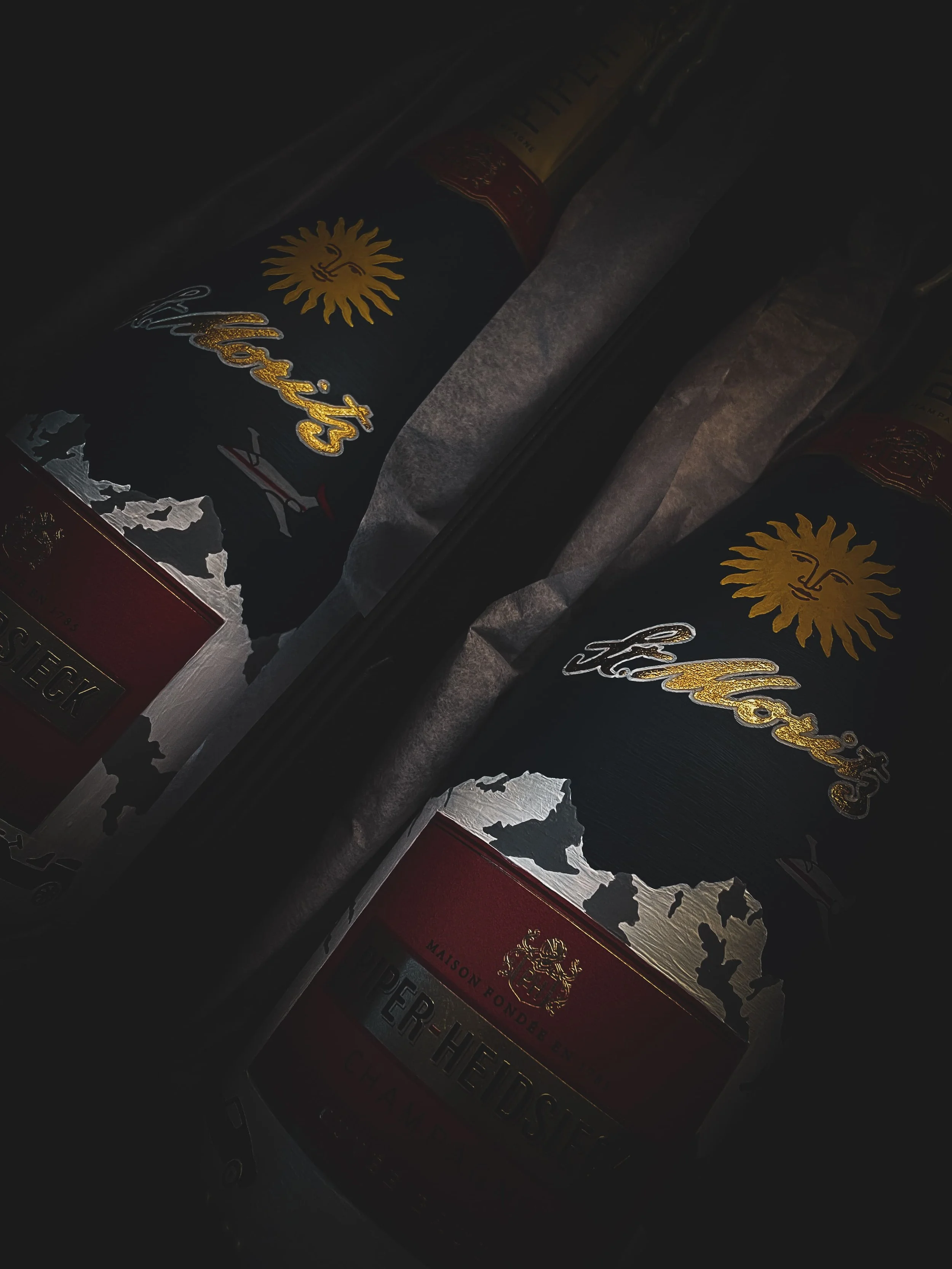 Hand-painted Piper-Heidsieck champagne bottles with St. Moritz sun motif and mountain design wrapped in tissue paper ready for delivery