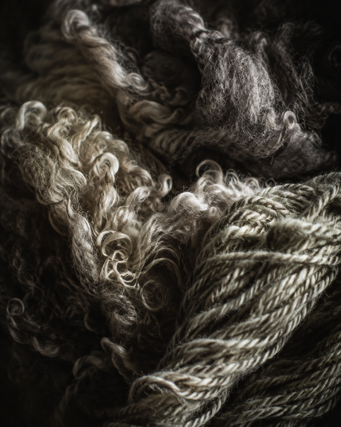 Close-up of a pile of tangled, frayed, and twisted yarns and fibers in shades of beige, gray, and dark brown.