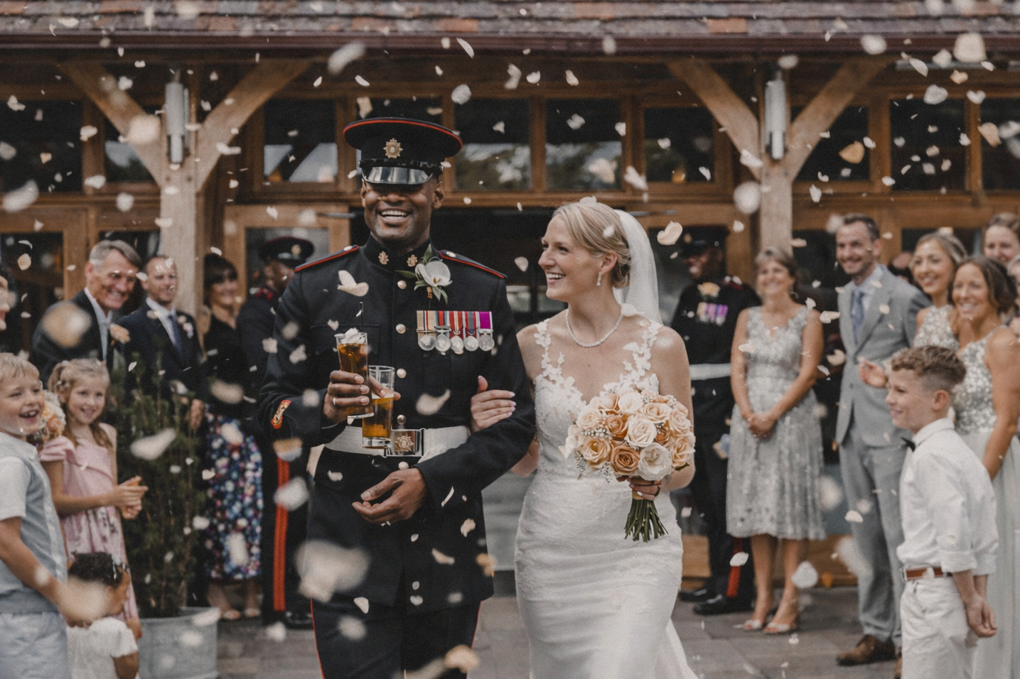 Bride and groom walking together at their wedding celebration, surrounded by guests and confetti.