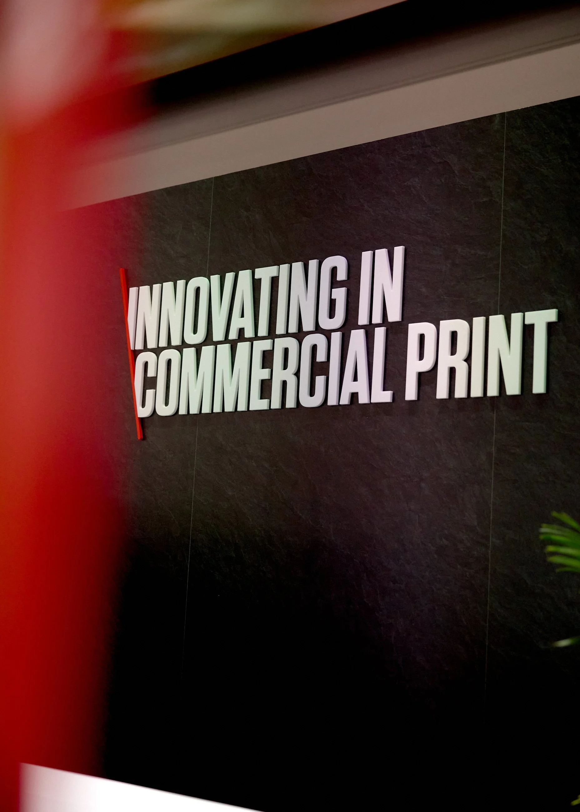 Sign on a dark wall that says 'Innovating in Commercial Print' with 3D letters