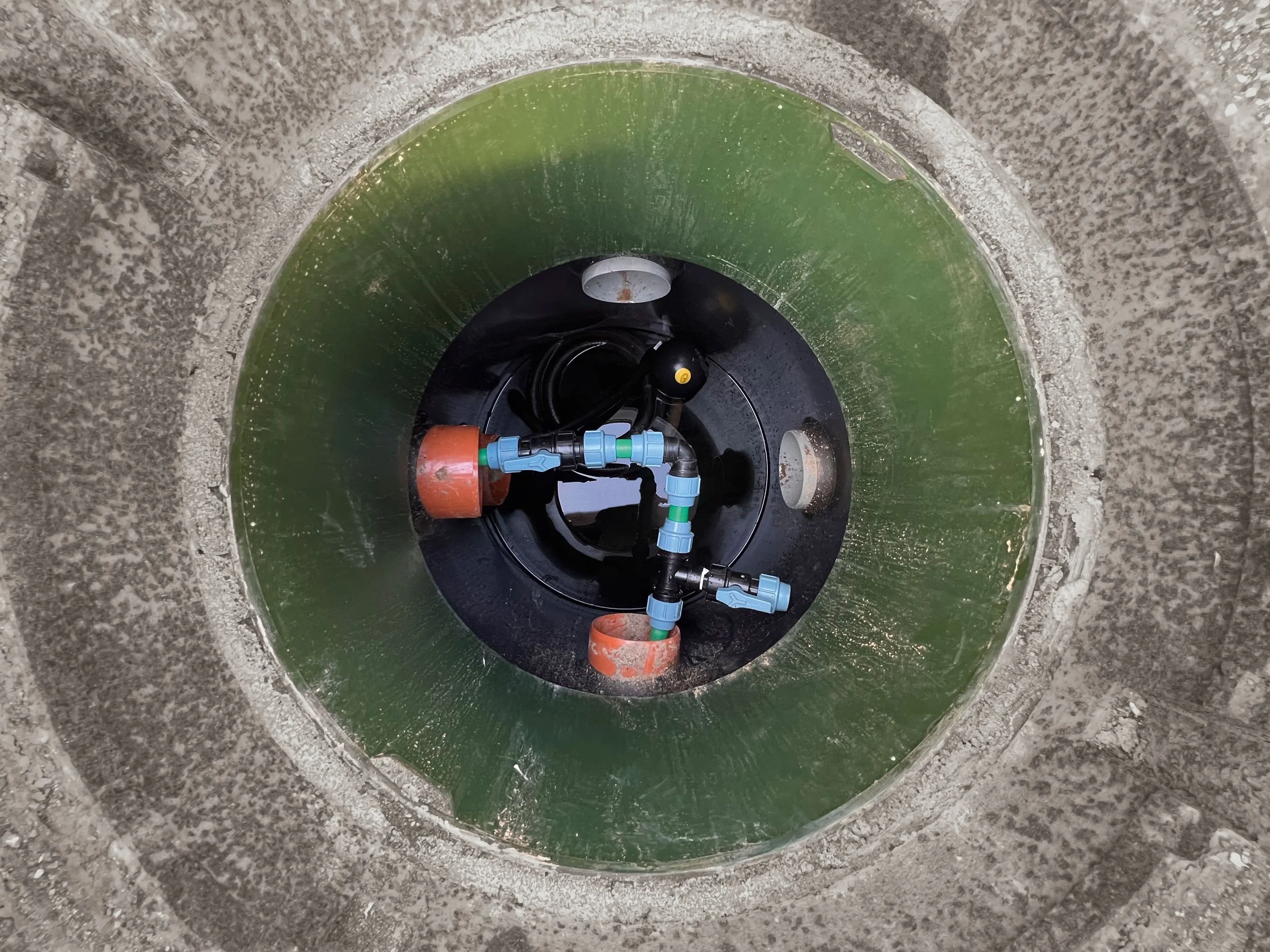 Blick in einen Brunnen mit Wasser und Installationen im Inneren.