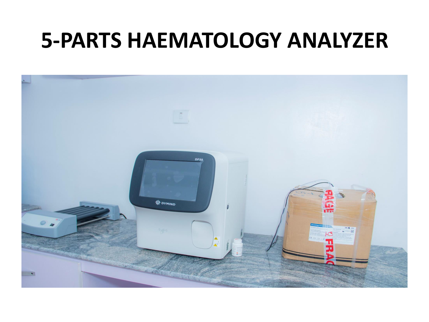Laboratory setup with a 5-part hematology analyzer, including a printer and a cardboard box labeled 'FRAGILE' on a marble countertop.