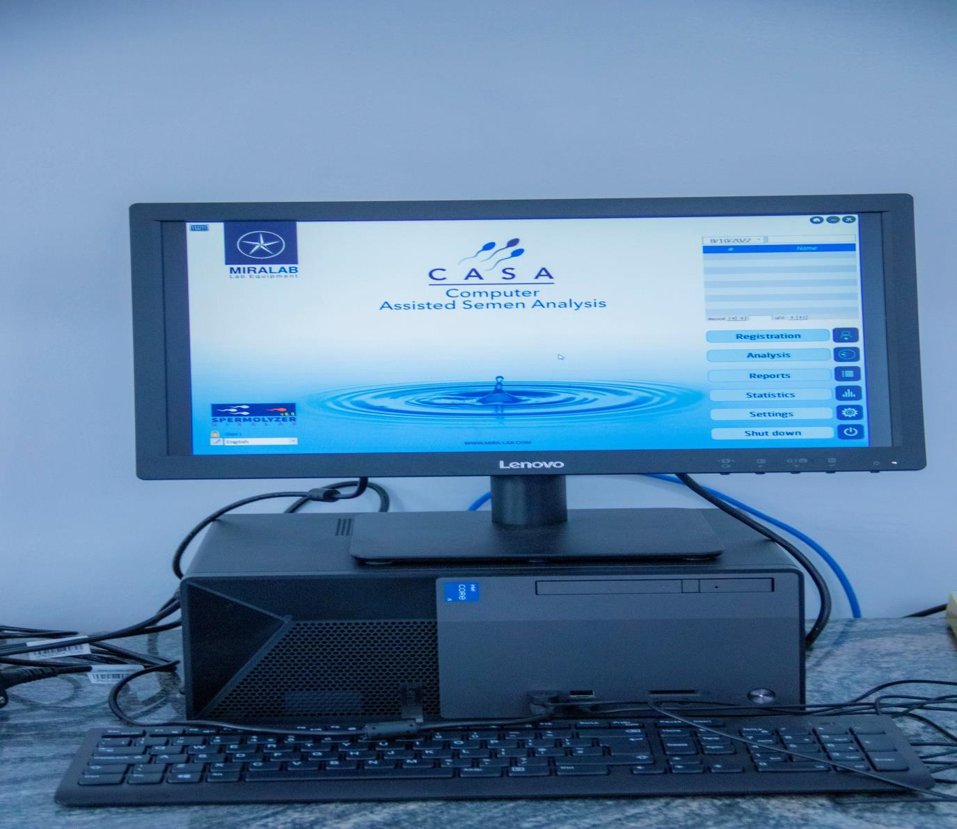Computer setup with monitor displaying CASA Assisted Semen Analysis software, keyboard, desktop tower, and various cables on a desk.