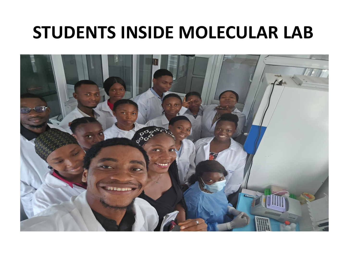 Group of students and instructors inside a molecular biology lab, posing for a group photo.