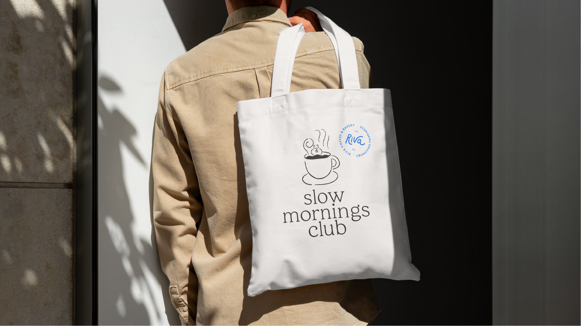Person with a white tote bag personalized with coffee and bakery logo.