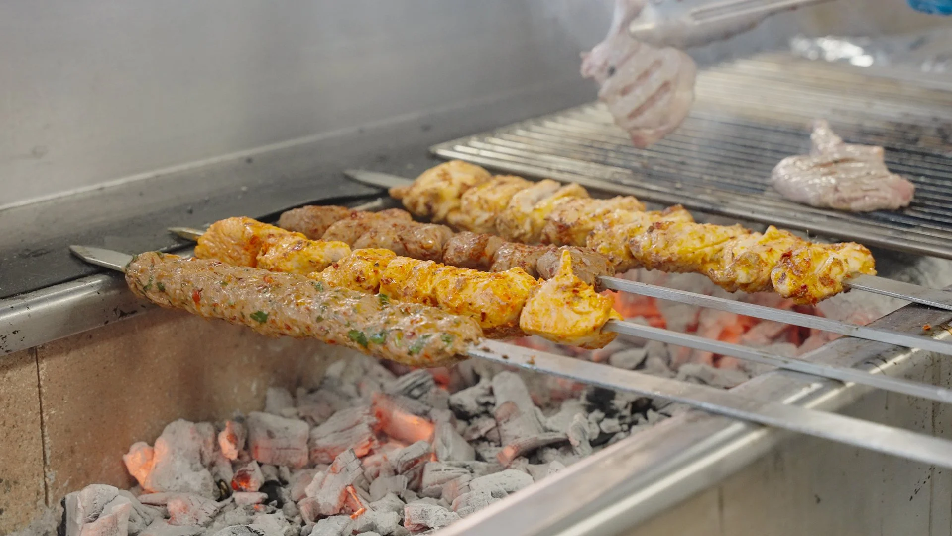 Skewers with marinated meat grilling over charcoal fire.