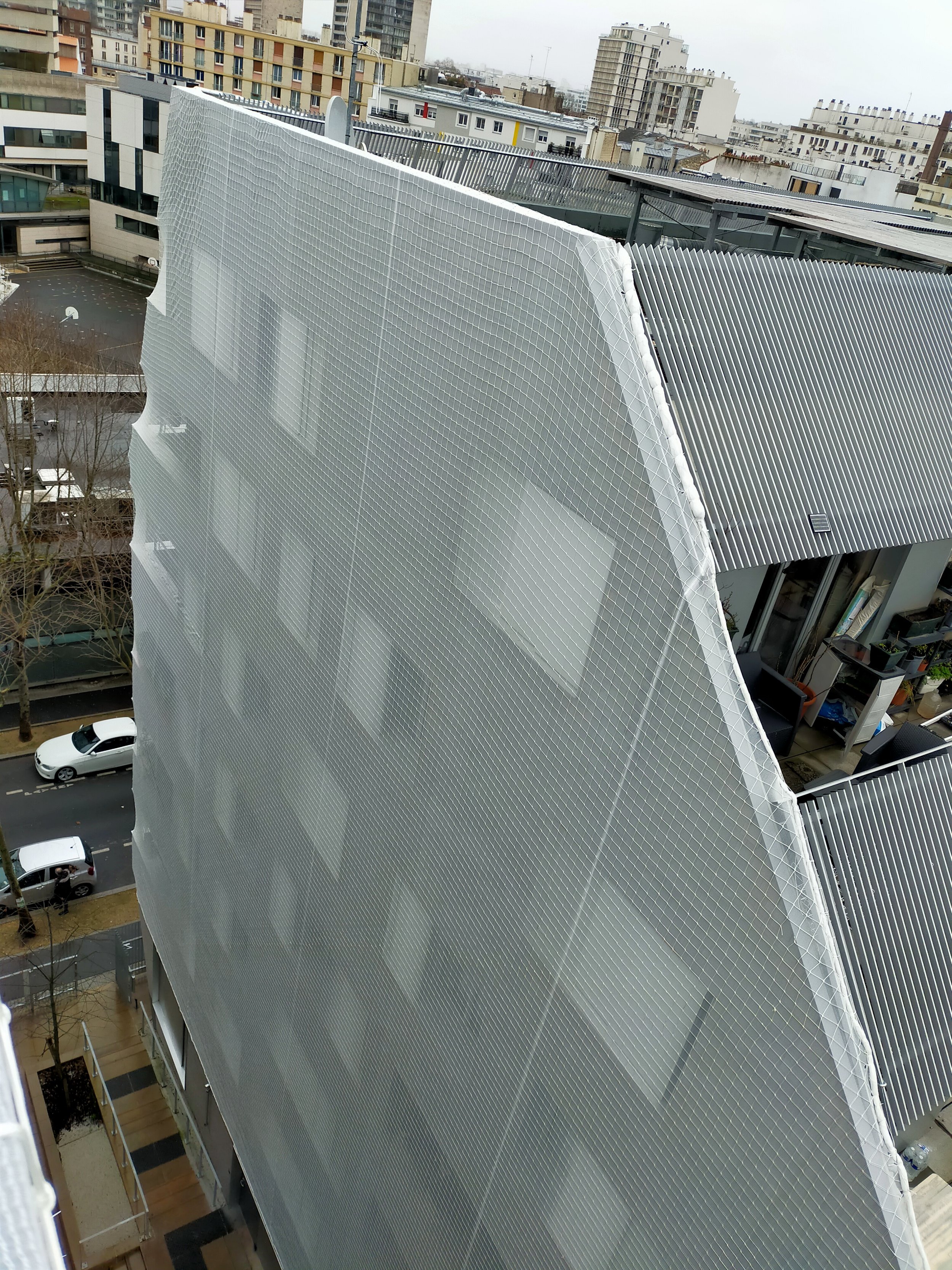 sécurisation d'une façade menacante par un filet anti chute de pierre par des cordistes