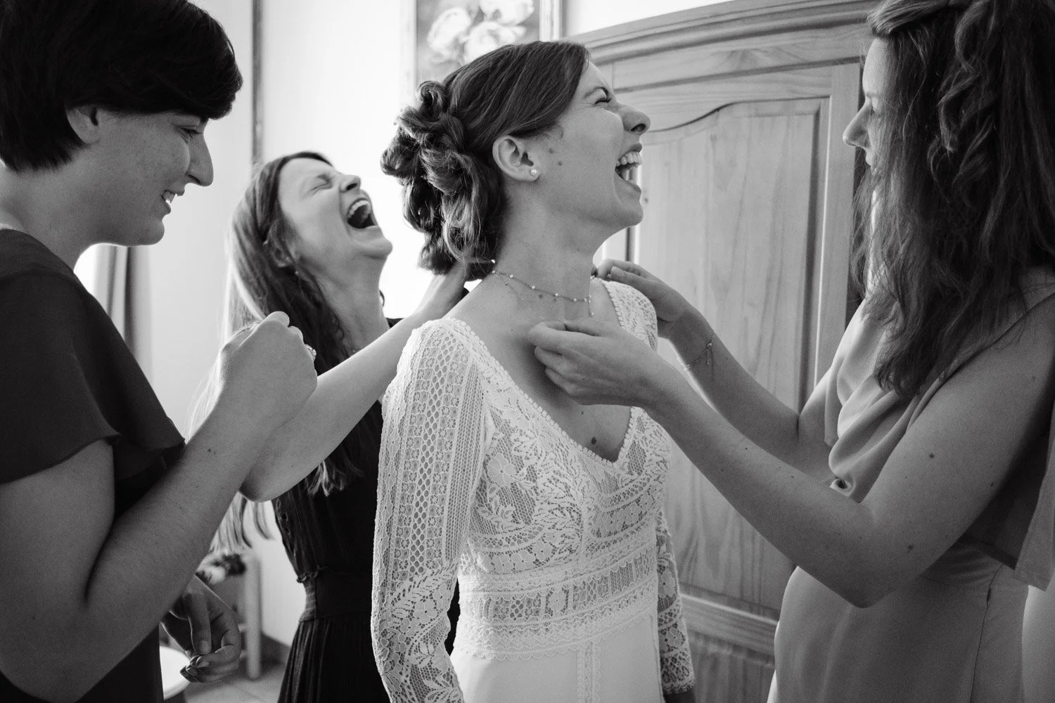 Un groupe de femmes souriantes et rieuses en préparation pour un mariage, entourant la mariée qui rit.