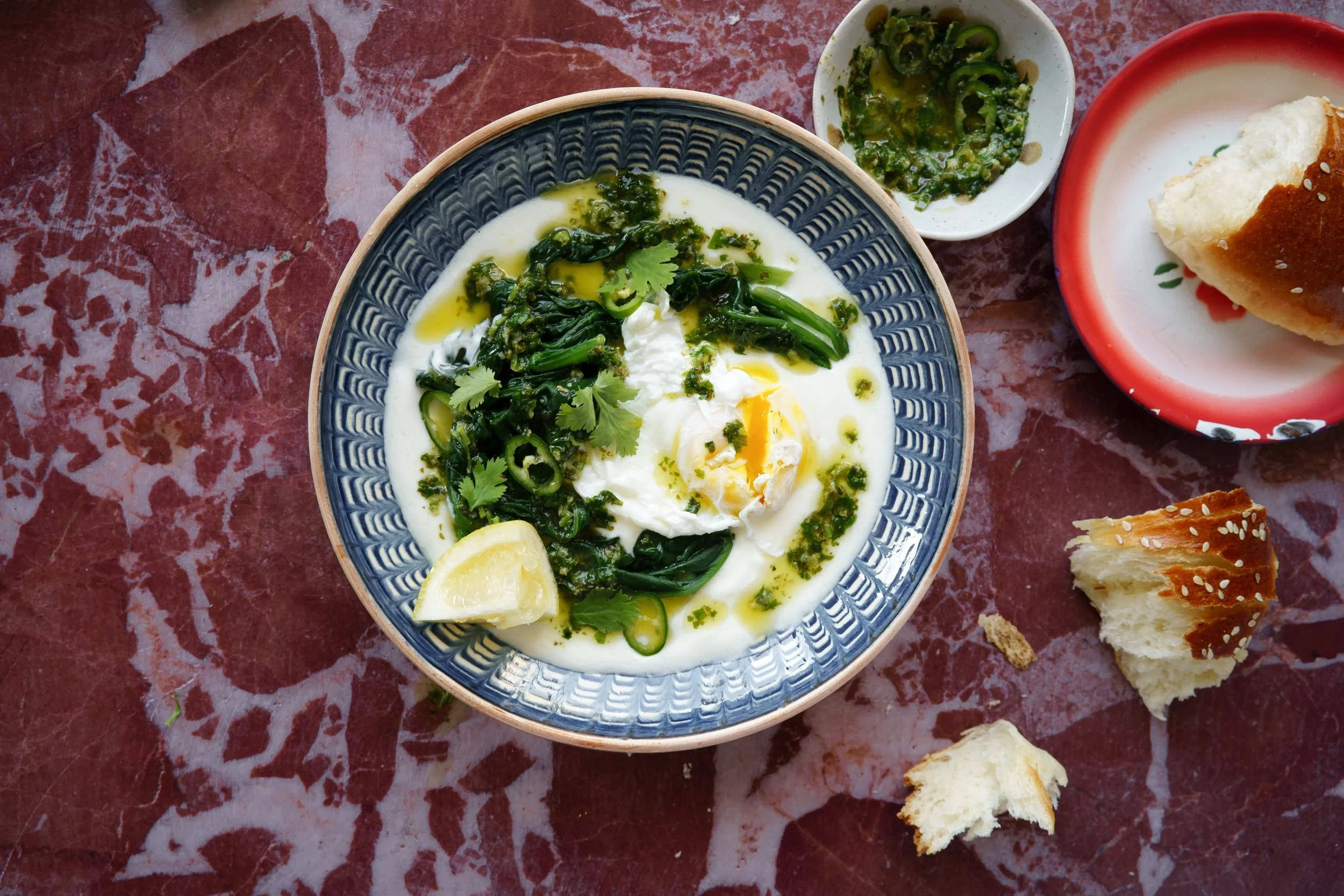 Rezeptentwicklung und Food Styling für Zeit.de Rezept: Ein Teller çilbir mit Joghurt, grünen Chilis, Koriander und Zitronenscheiben, daneben kleine Schüssel mit grüner Chilipaste und aufgeteilt Brotstücke.