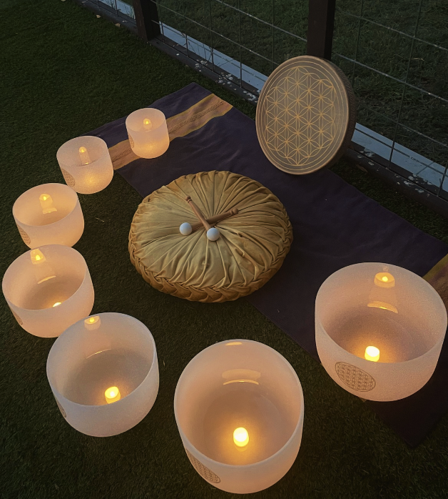Glowing singing bowls, ocean drum and sit cushion displayed in an outdoor setting at night.