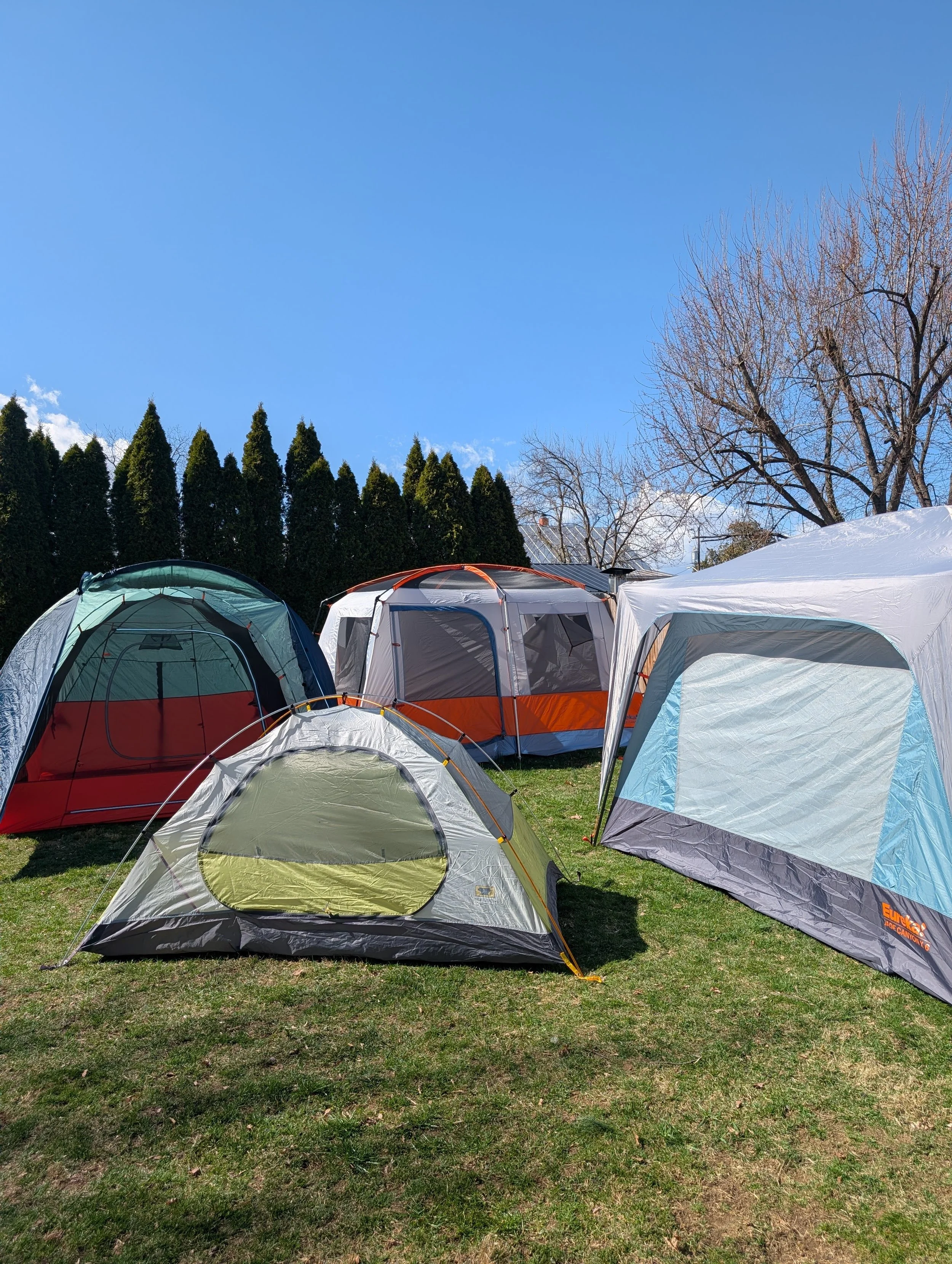 Used camping tents laying over grass