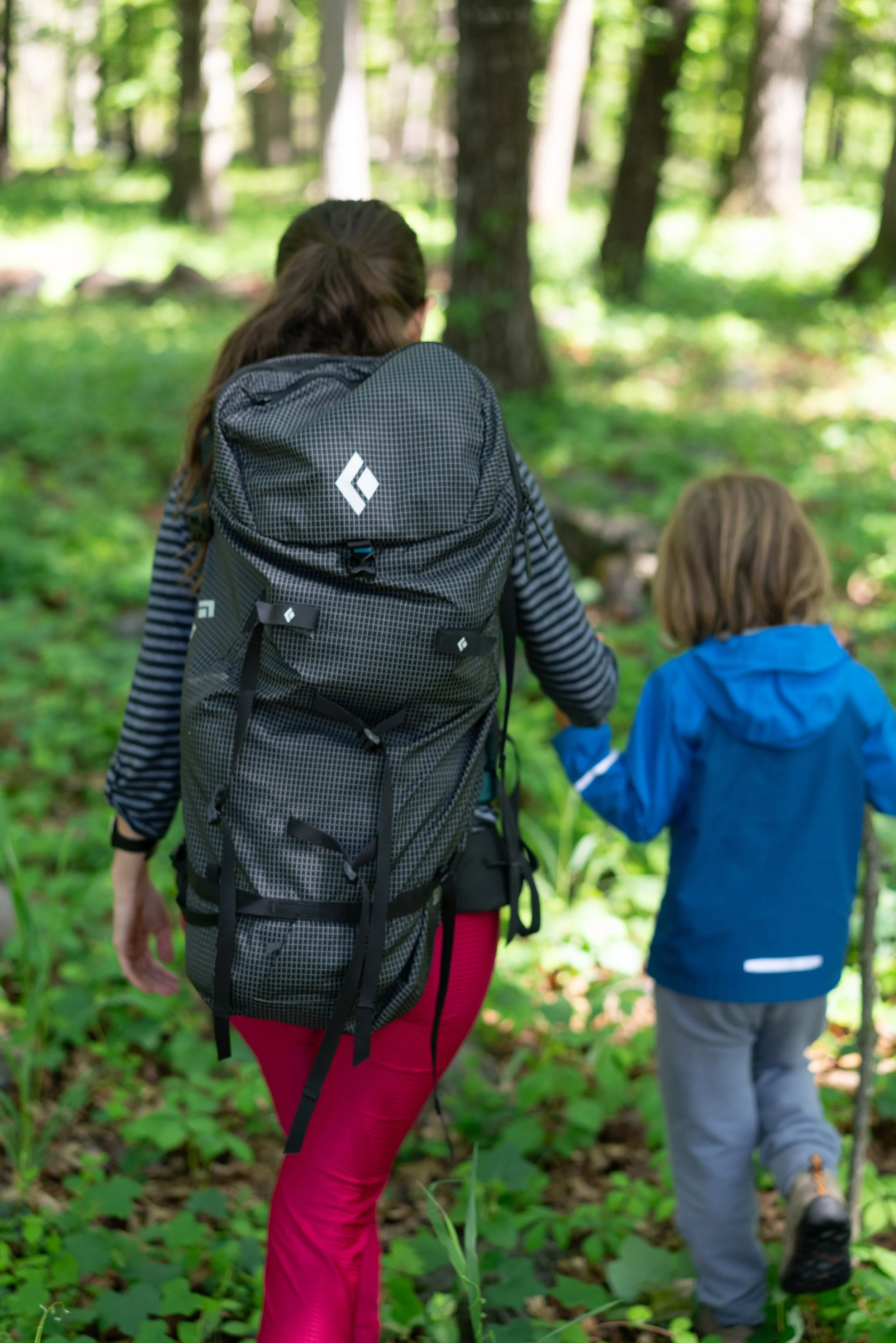 Woman wearing a used Black Diamond backpack hikes holding hands with a boy wearing a used Patagonia jacket