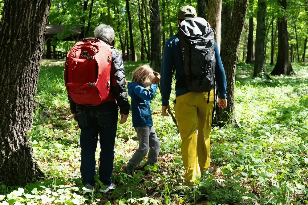 Grandpa, father and son hiking and wearing used Osprey and Black Diamond backpacks