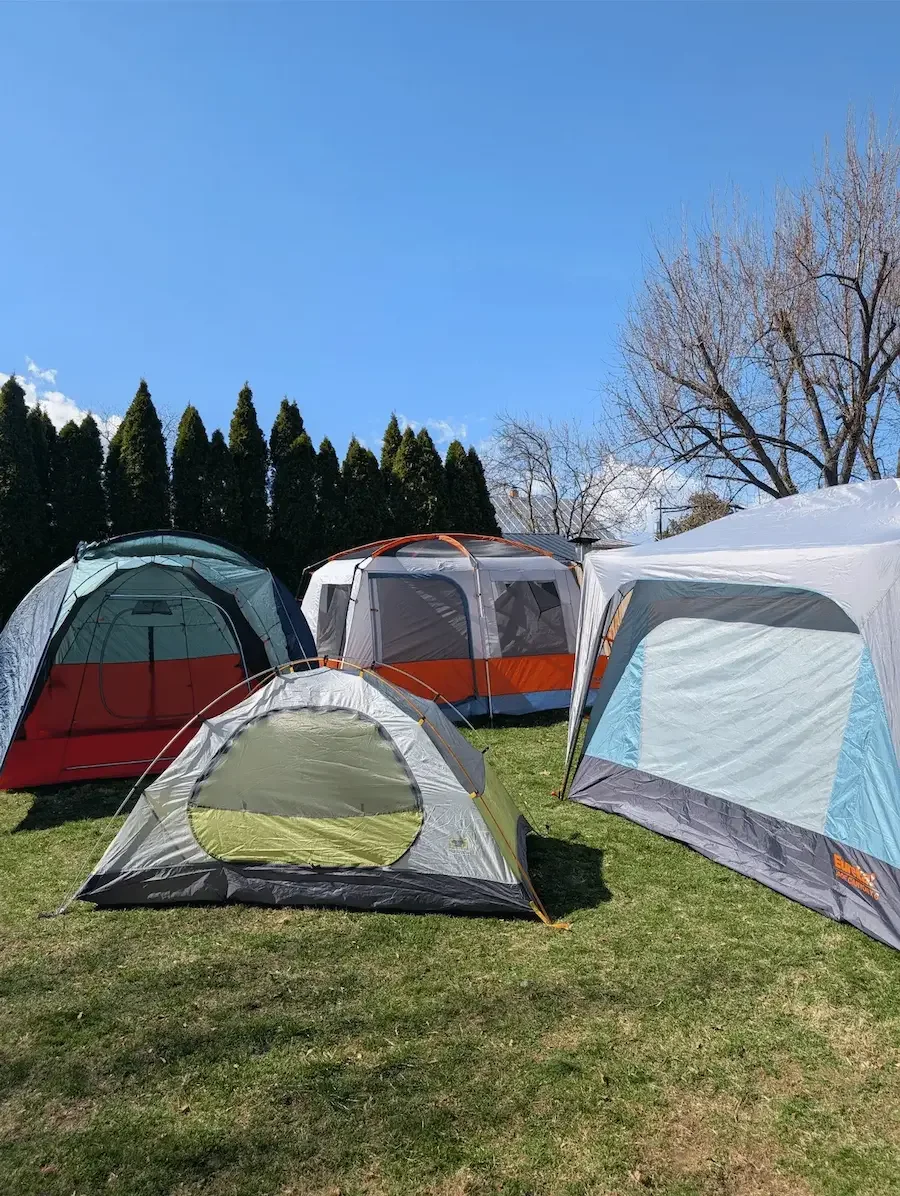 Used camping tents laying over grass