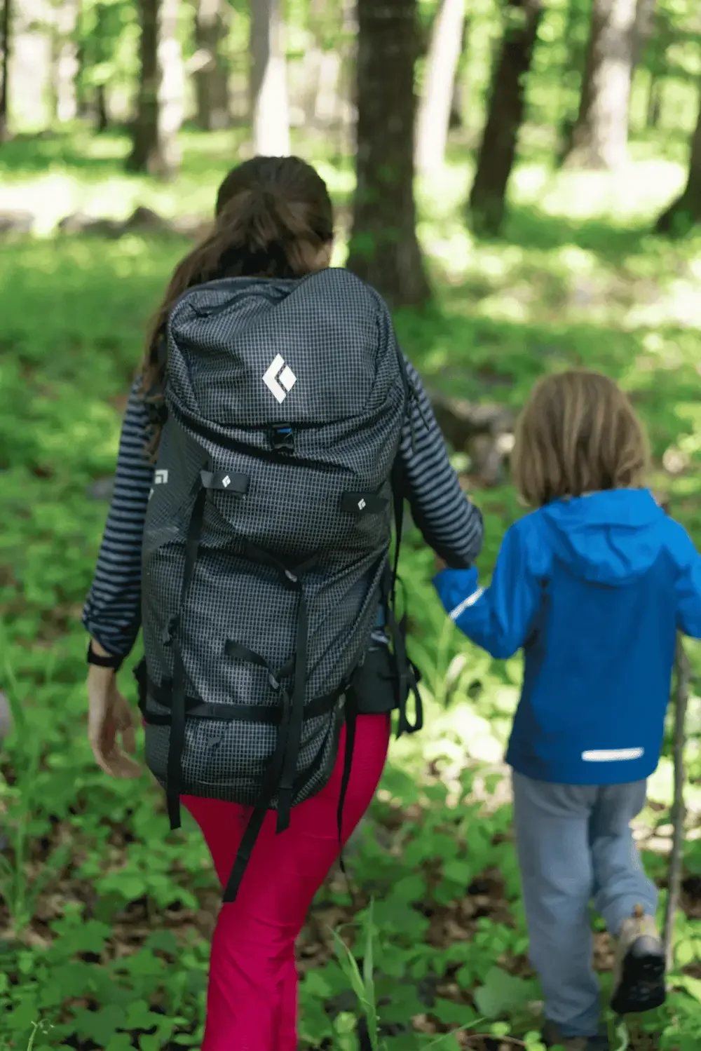 Woman wearing a used Black Diamond backpack hikes holding hands with a boy wearing a used Patagonia jacket