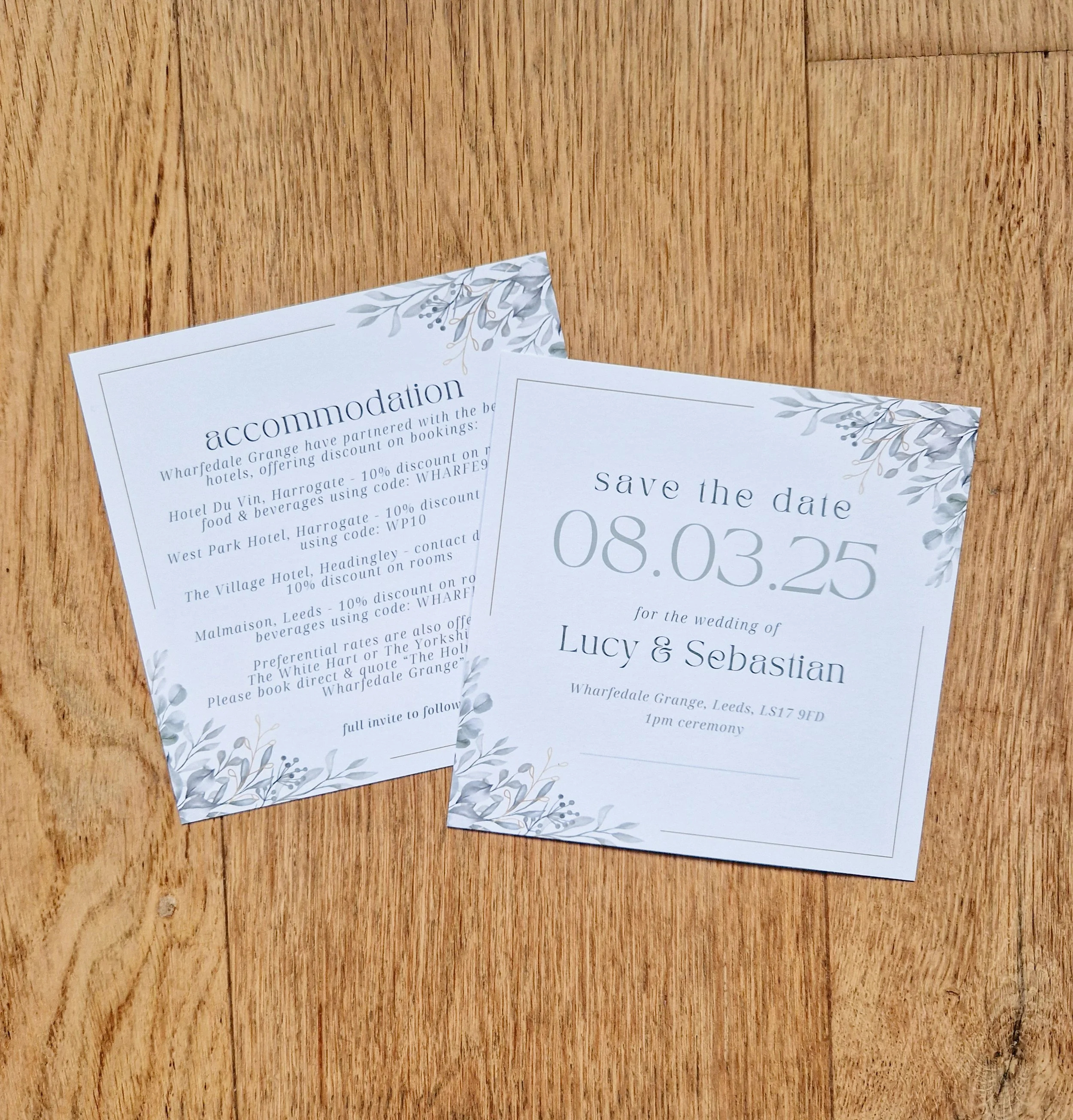Square double sided Wedding save-the-date card and accommodation information card on a wooden surface. The cards have sage floral designs and elegant text. Wharfedale Grange Leeds