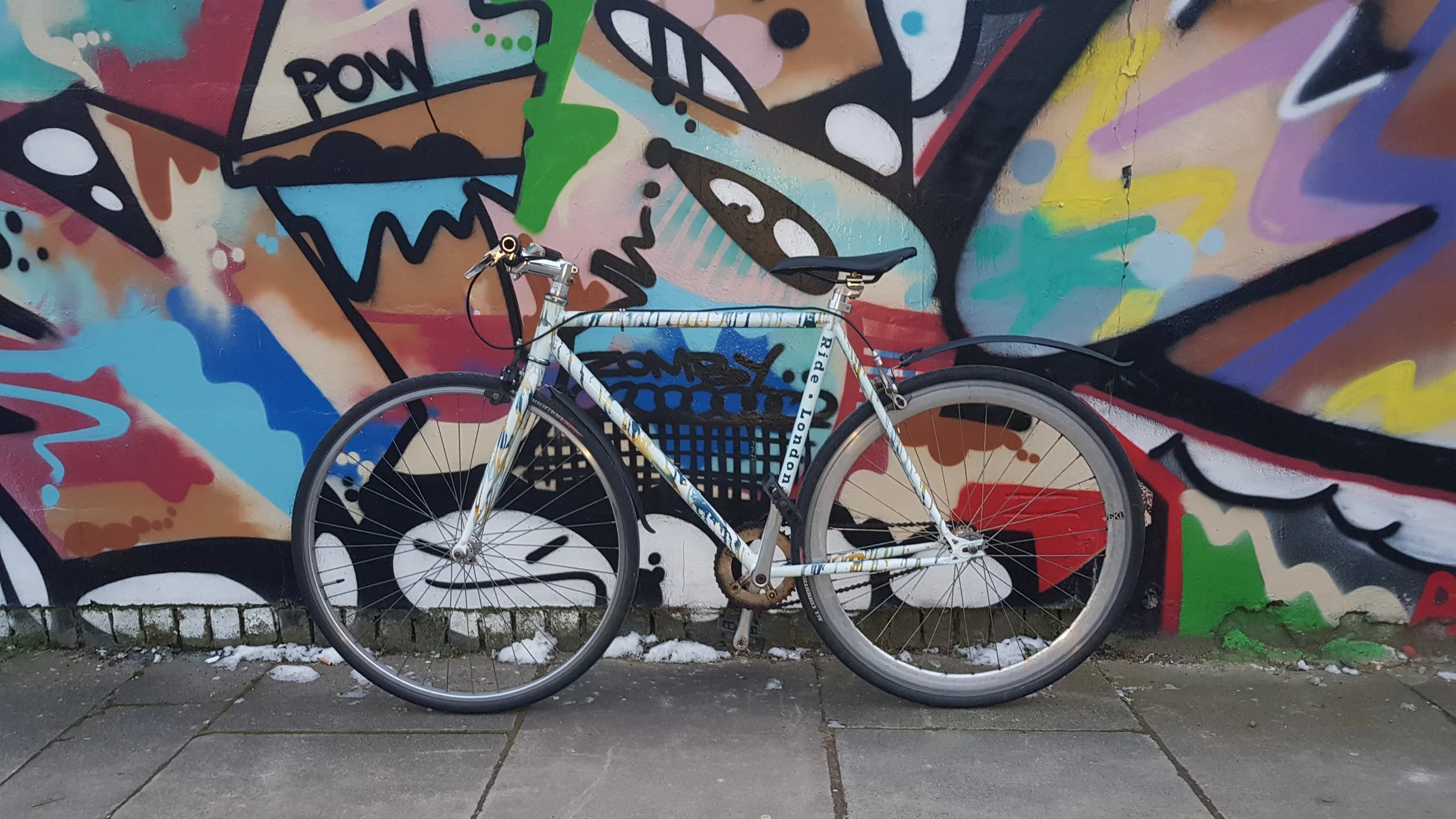 A bicycle leaning against a colorful graffiti wall featuring various abstract shapes and patterns.