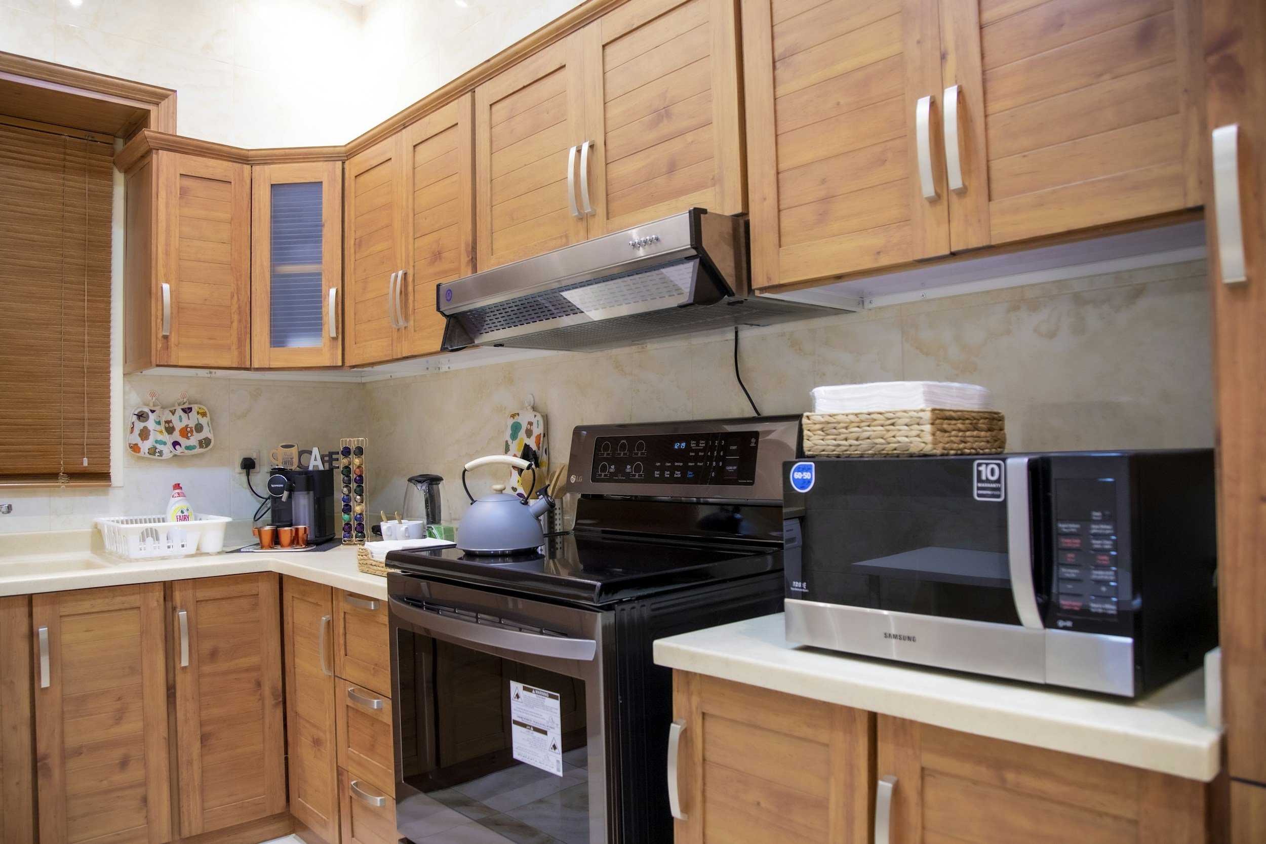 Kitchen with wooden cabinets, black stove, microwave, and kettle on the countertop.
