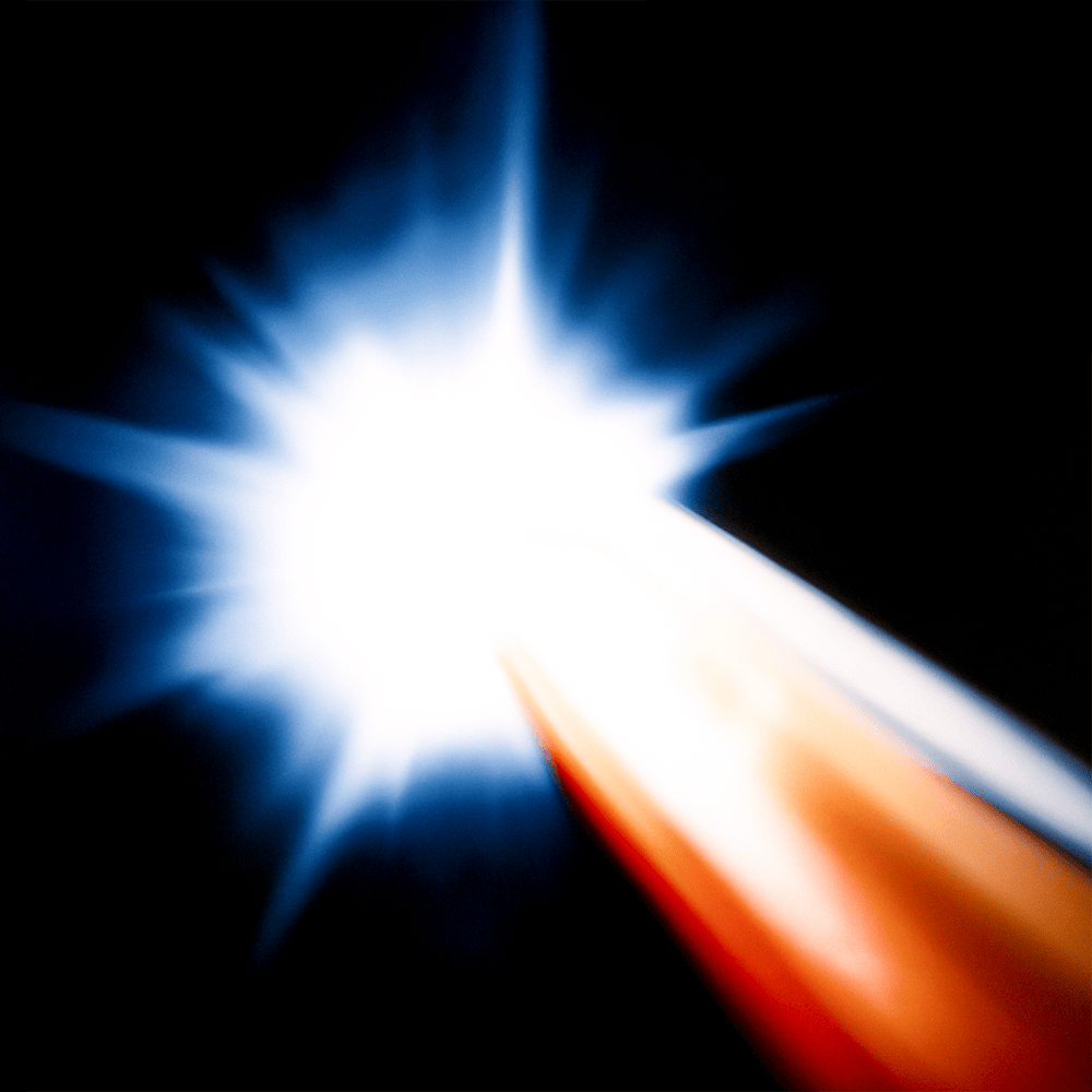 Una luce molto brillante, con raggi blu e bianchi, che si irradiano da un centro luminoso, con un contrasto forte con lo sfondo nero.