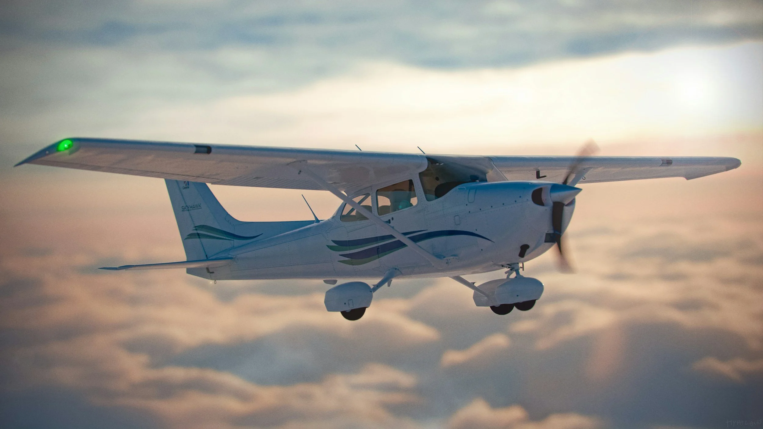 A small white airplane flying above clouds during sunset or sunrise.