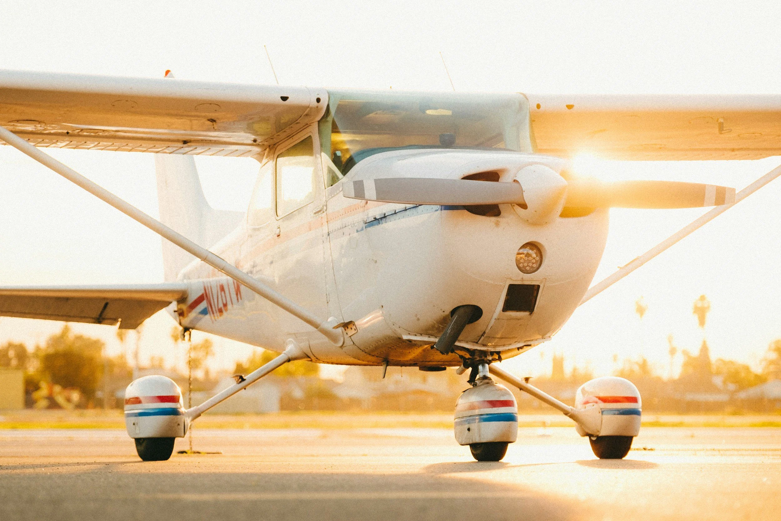 Small white airplane on airport tarmac during sunset, with sunlight shining from the right side.