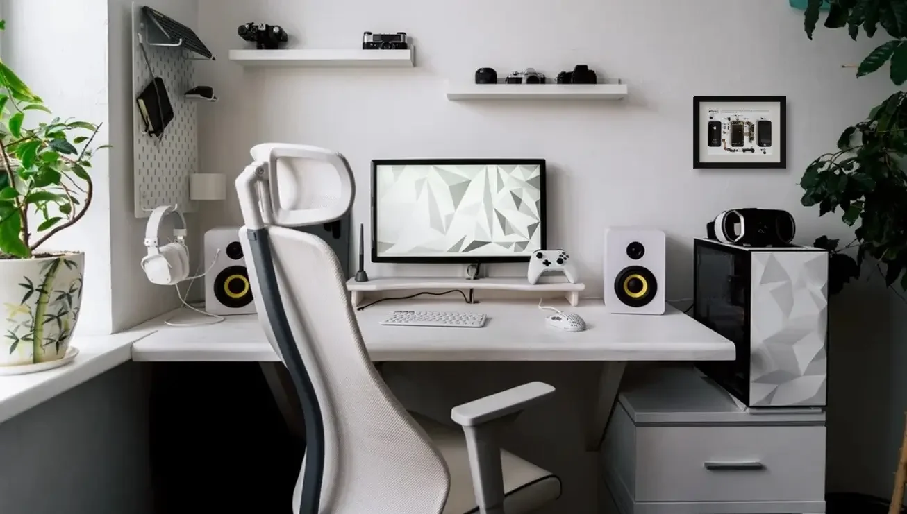 Modern computer desk setup with a white ergonomic chair, monitor, keyboard, mouse, and gaming controller, surrounded by shelves with cameras and headphones, speakers, a mini fridge, black and white decor, and potted plants.