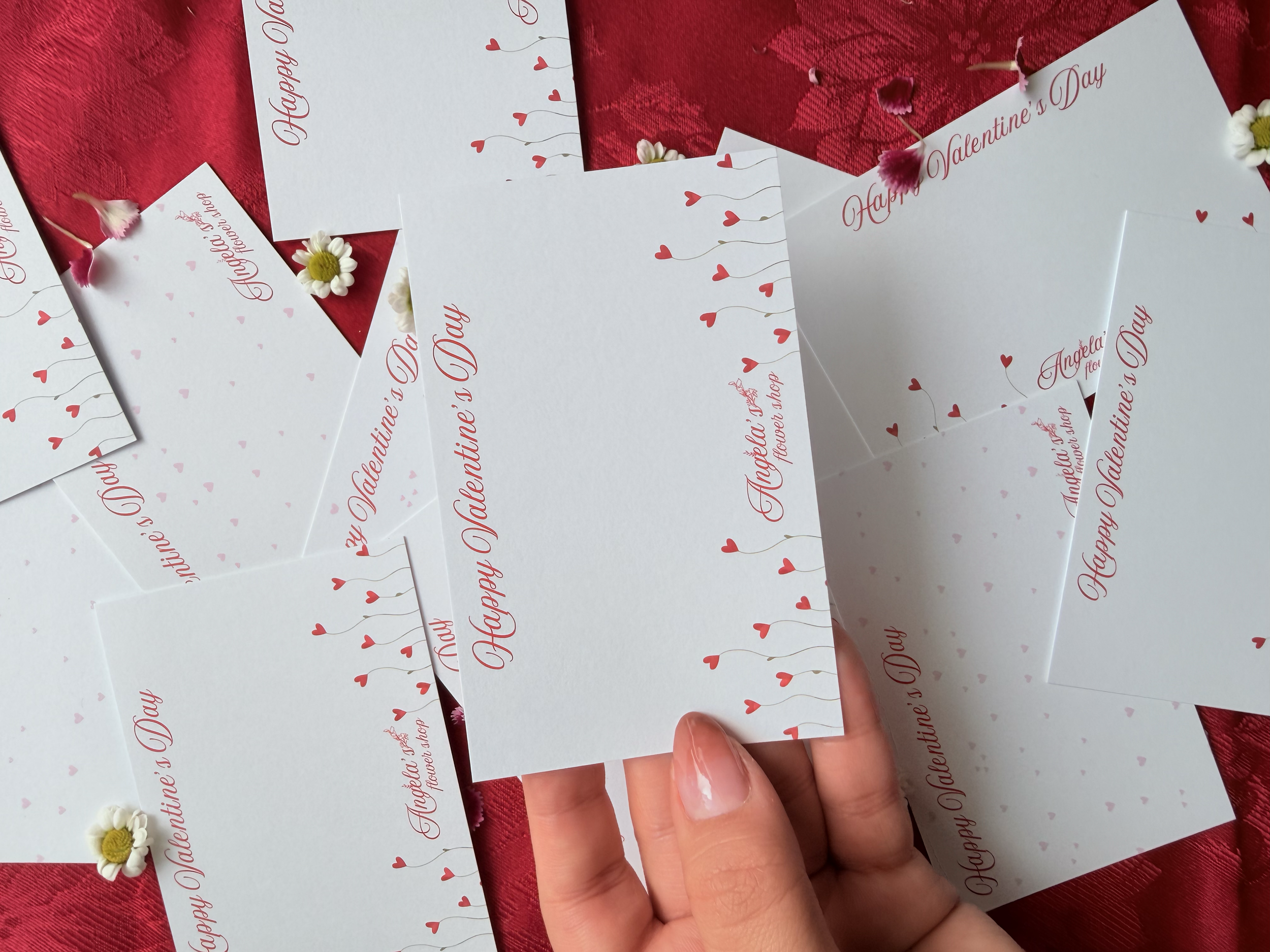 Valentine's Day cards for a local flower shop with red hearts and pink decorations on a red fabric background