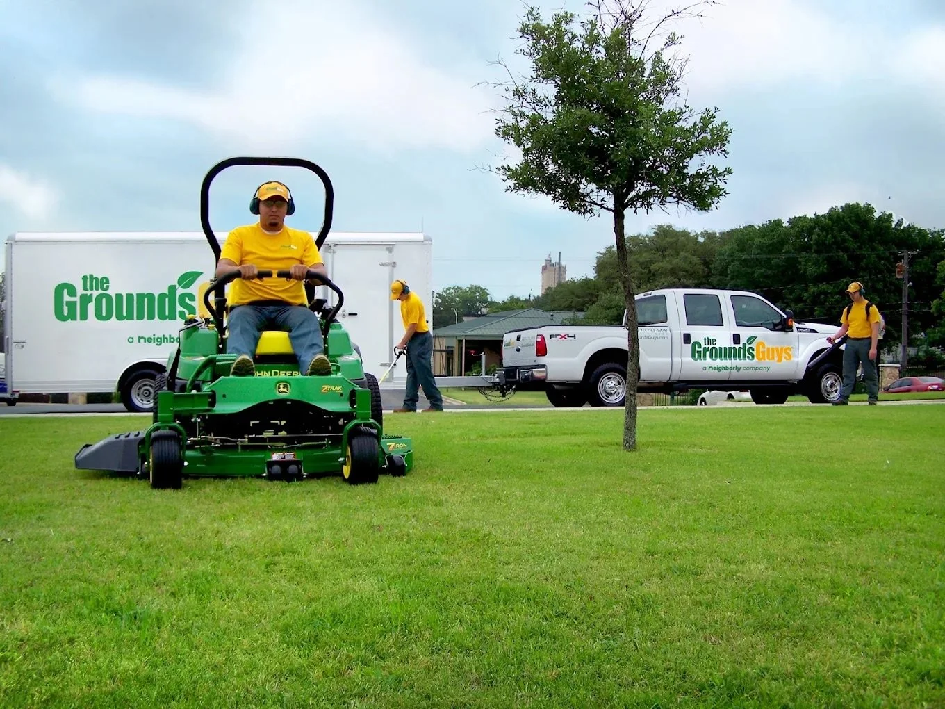 Professional lawn and grounds maintenance crew mowing, trimming, and blowing grass clippings at a commercial property in New Lenox, Illinois.